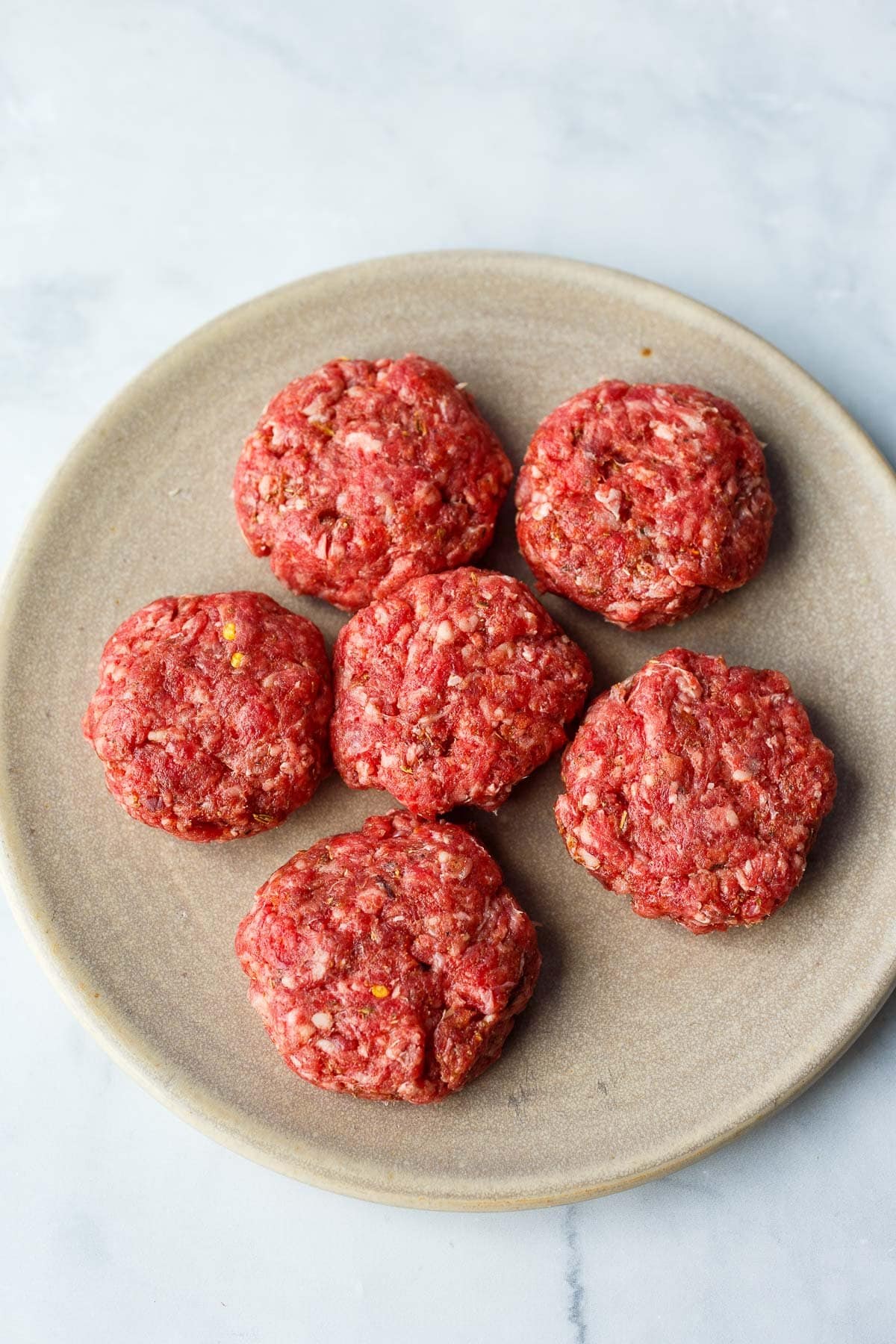 Italian sausage formed into patties on plate. 