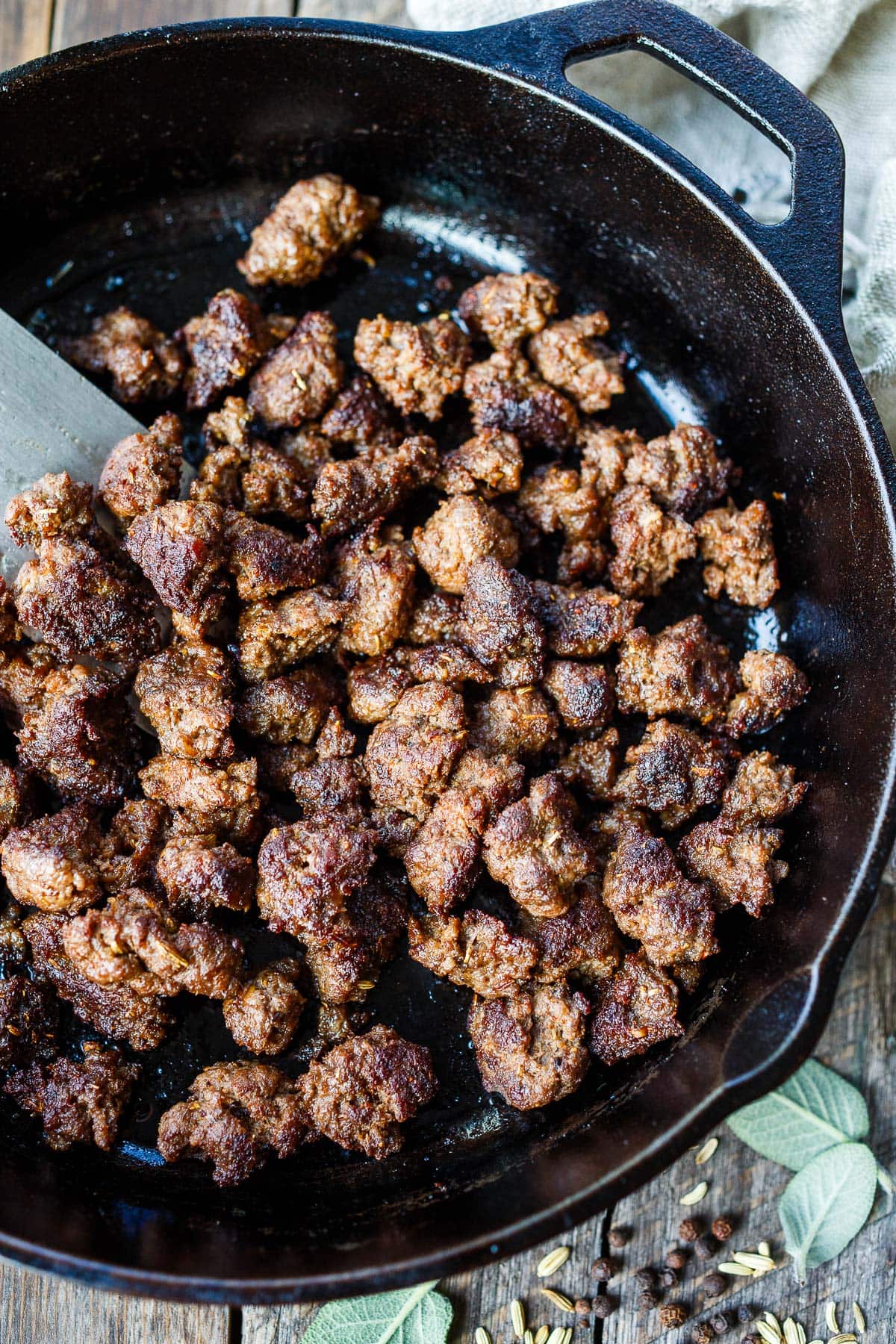 using spatula to stir homemade Italian sausage crumbles in cast iron skillet. 