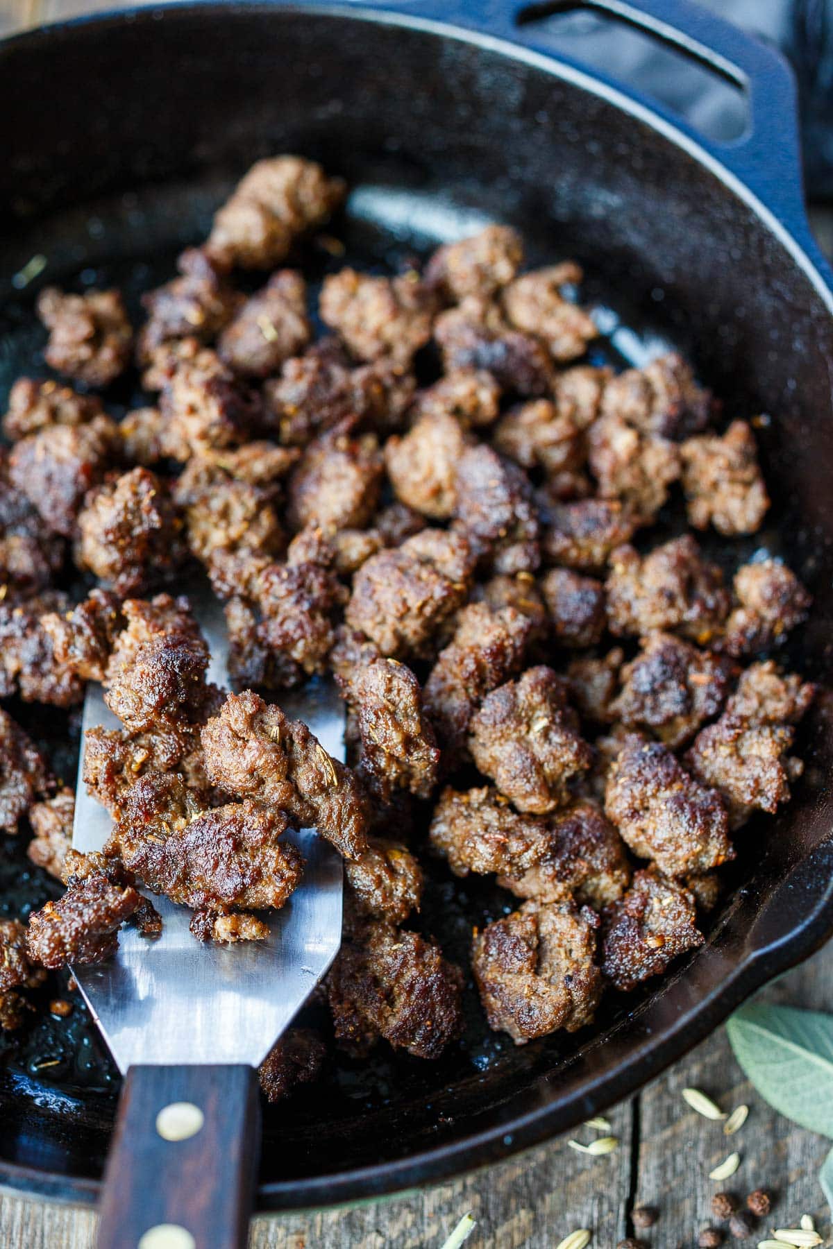 spatula lifting homemade Italian sausage crumbles from cast iron skillet. 