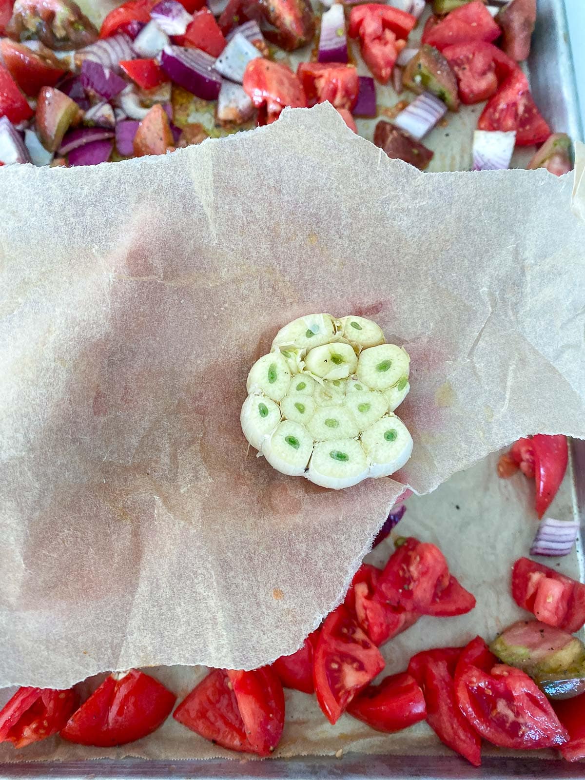 raw garlic head on parchment with top sliced off.