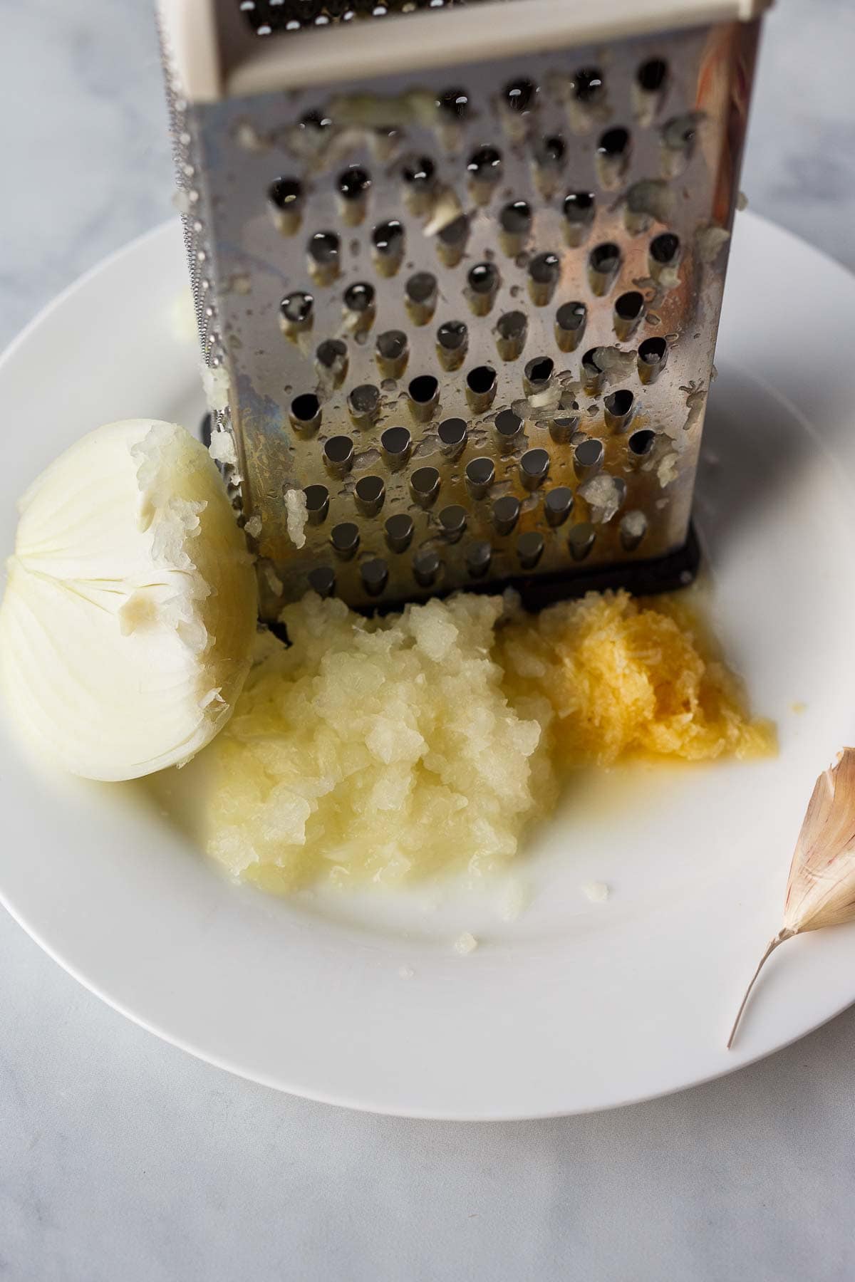 grater on dish with grated onion and garlic. 