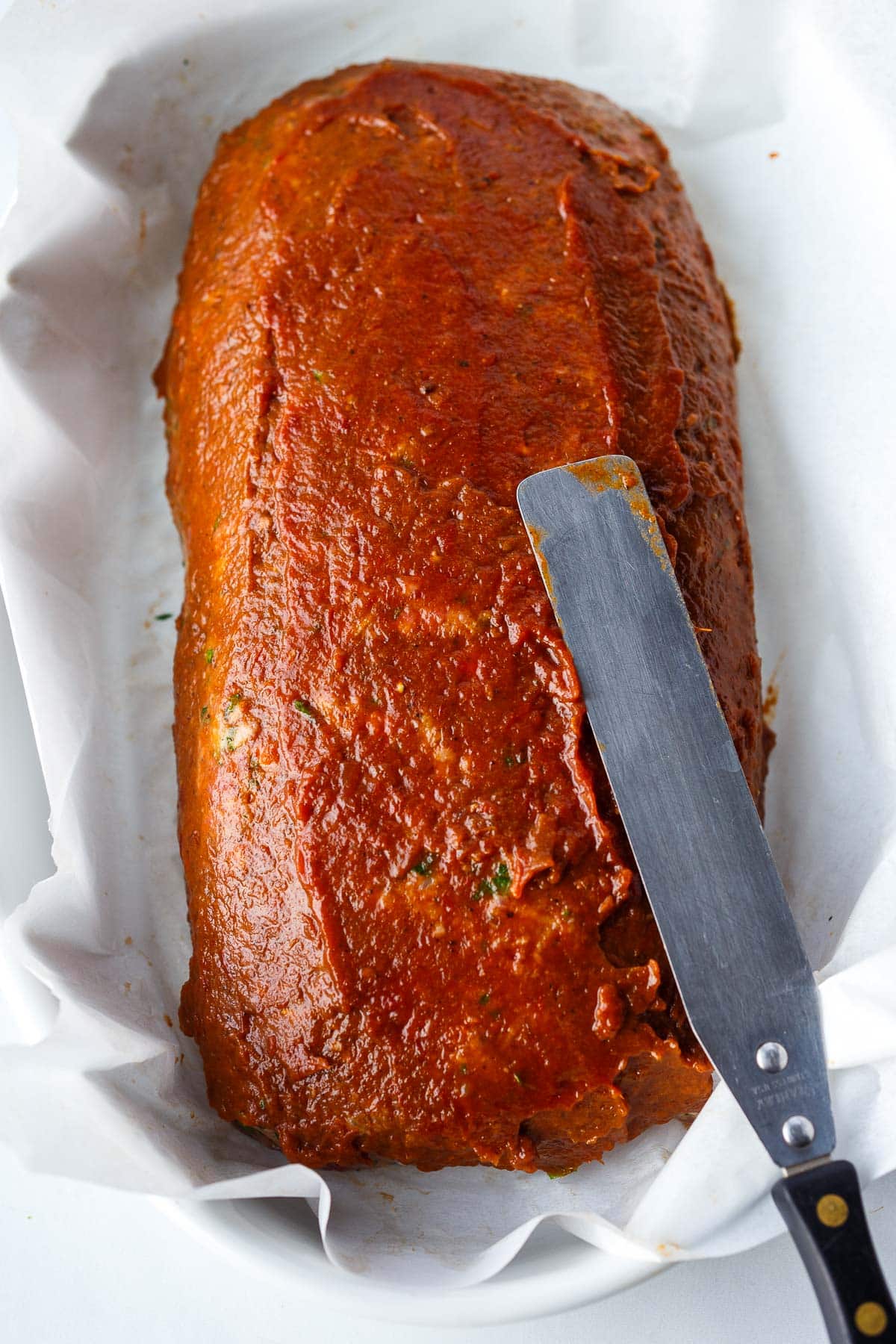 spreading jammy roasted ketchup on meatloaf. 