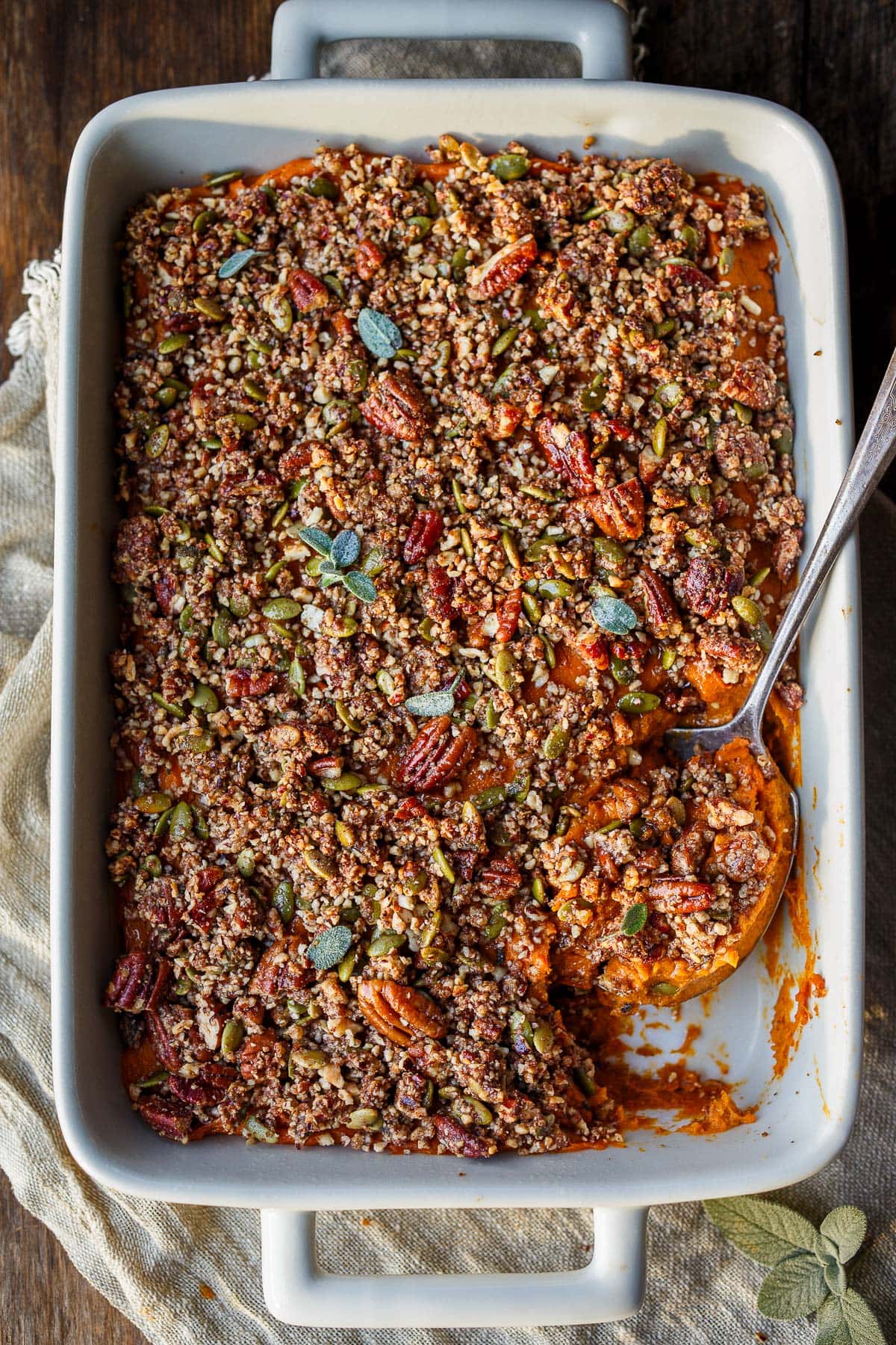 sweet potato casserole with pecan crumble topping and spoon scooping out a serving.