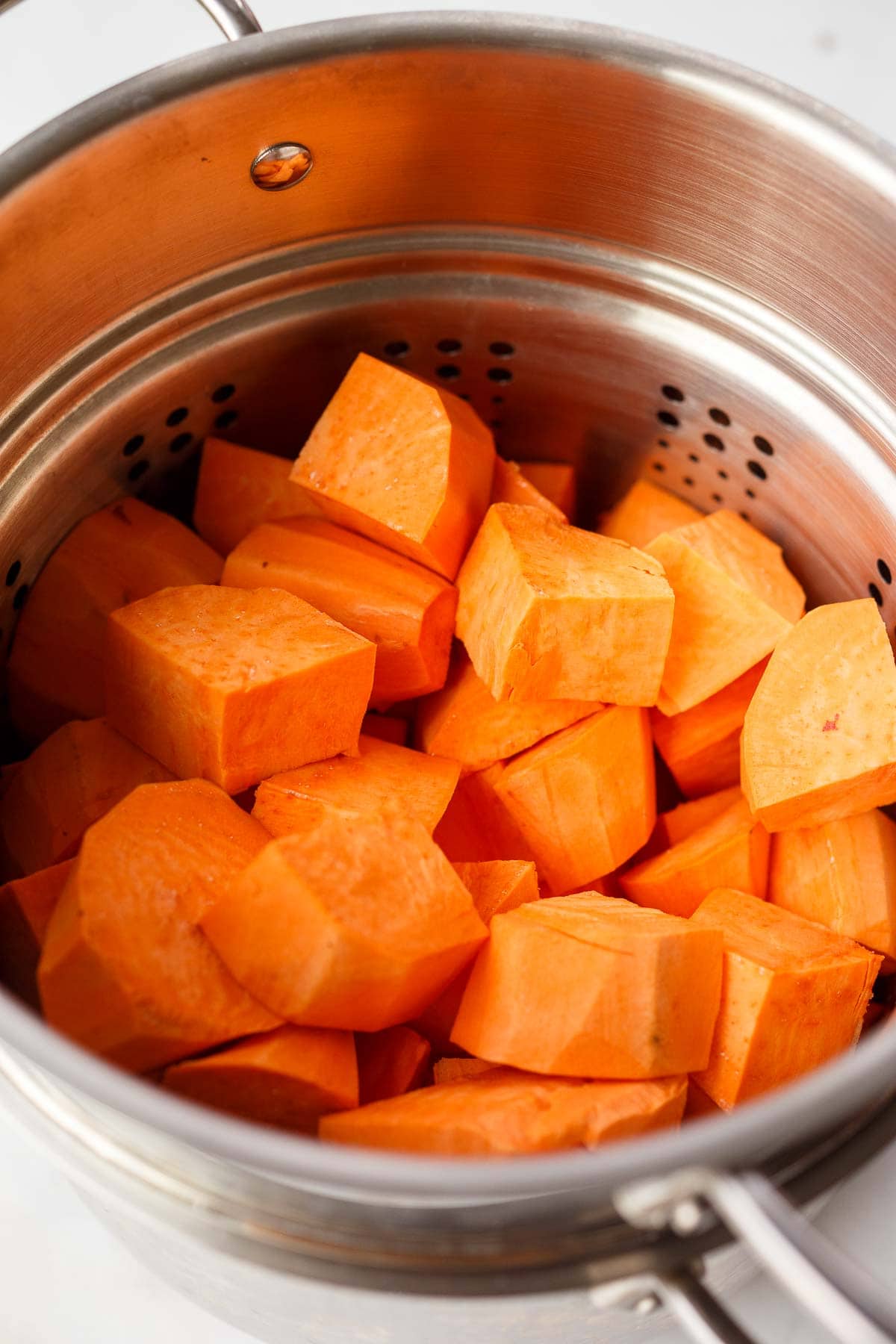 chopped sweet potatoes in steamer basket.