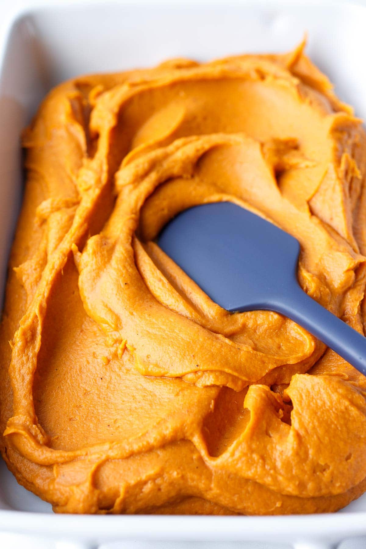 sweet potato mixture spread out with spatula in casserole dish.