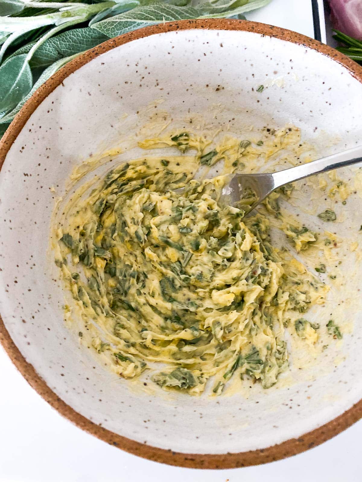 small bowl with softened herbed butter and fork to mix.