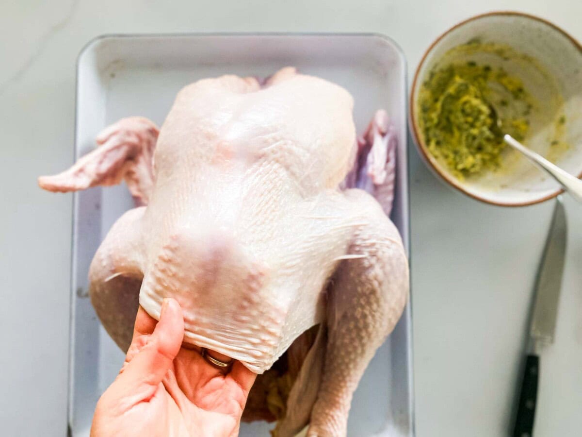hand rubbing herbed butter underneath the turkey skin.