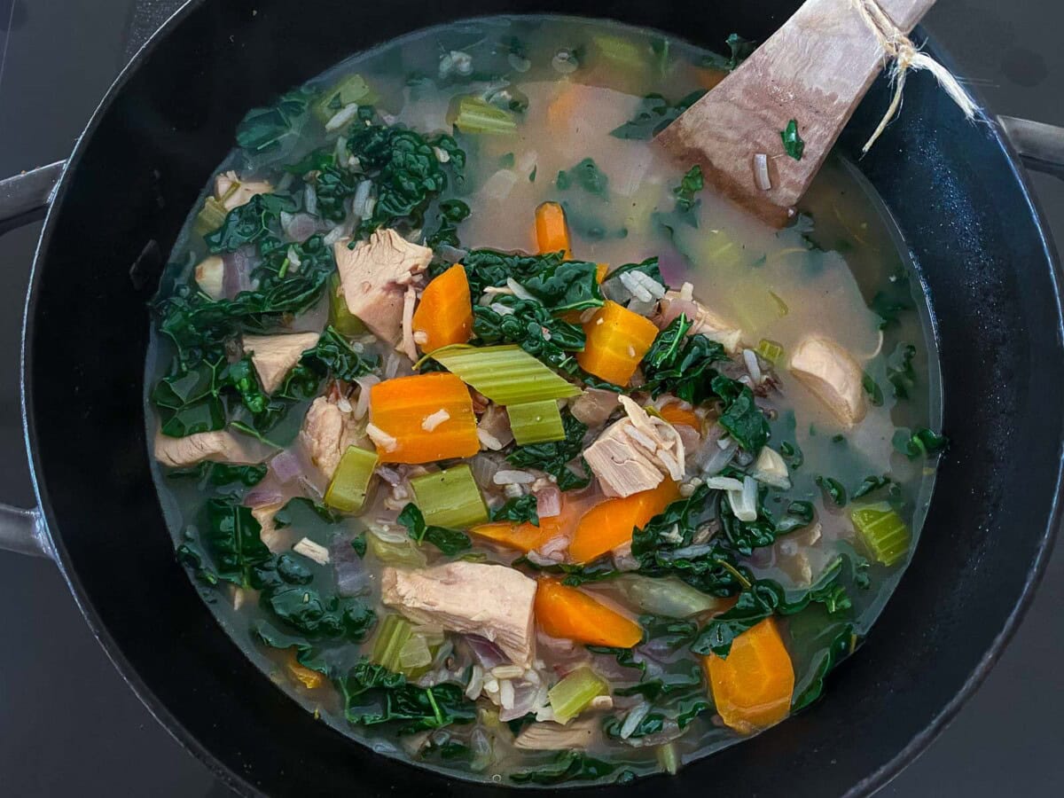 turkey rice soup in large pot with lacinato kale.