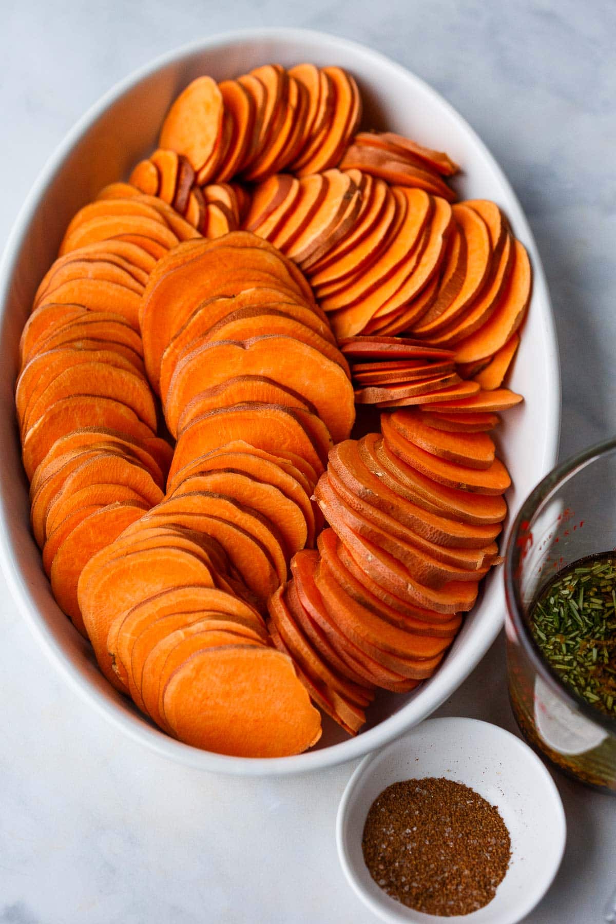 arranging sliced yams in spiral in oval baking dish. 