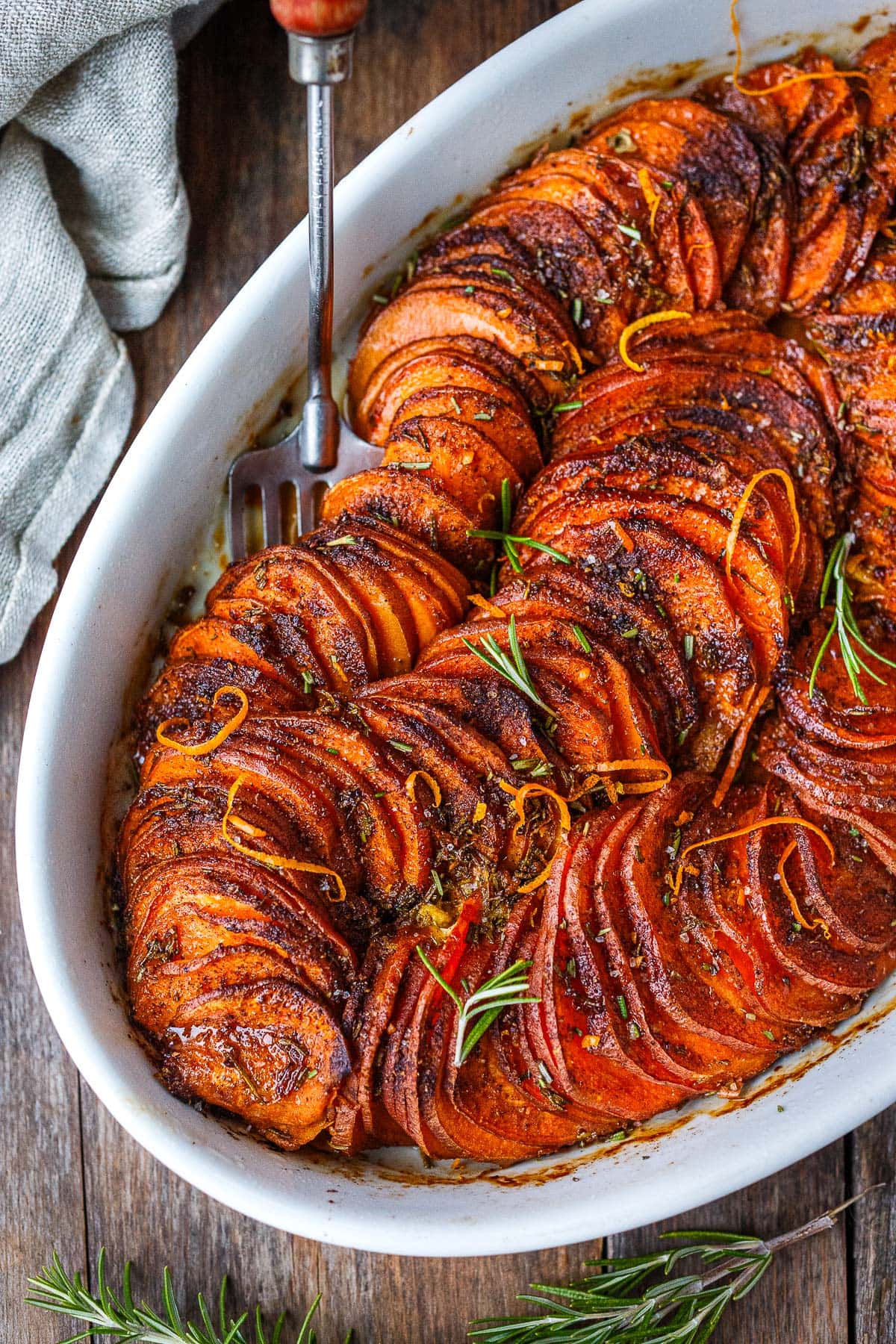 vegan sweet potato casserole in oval serving dish with orange zest and fresh herbs. 