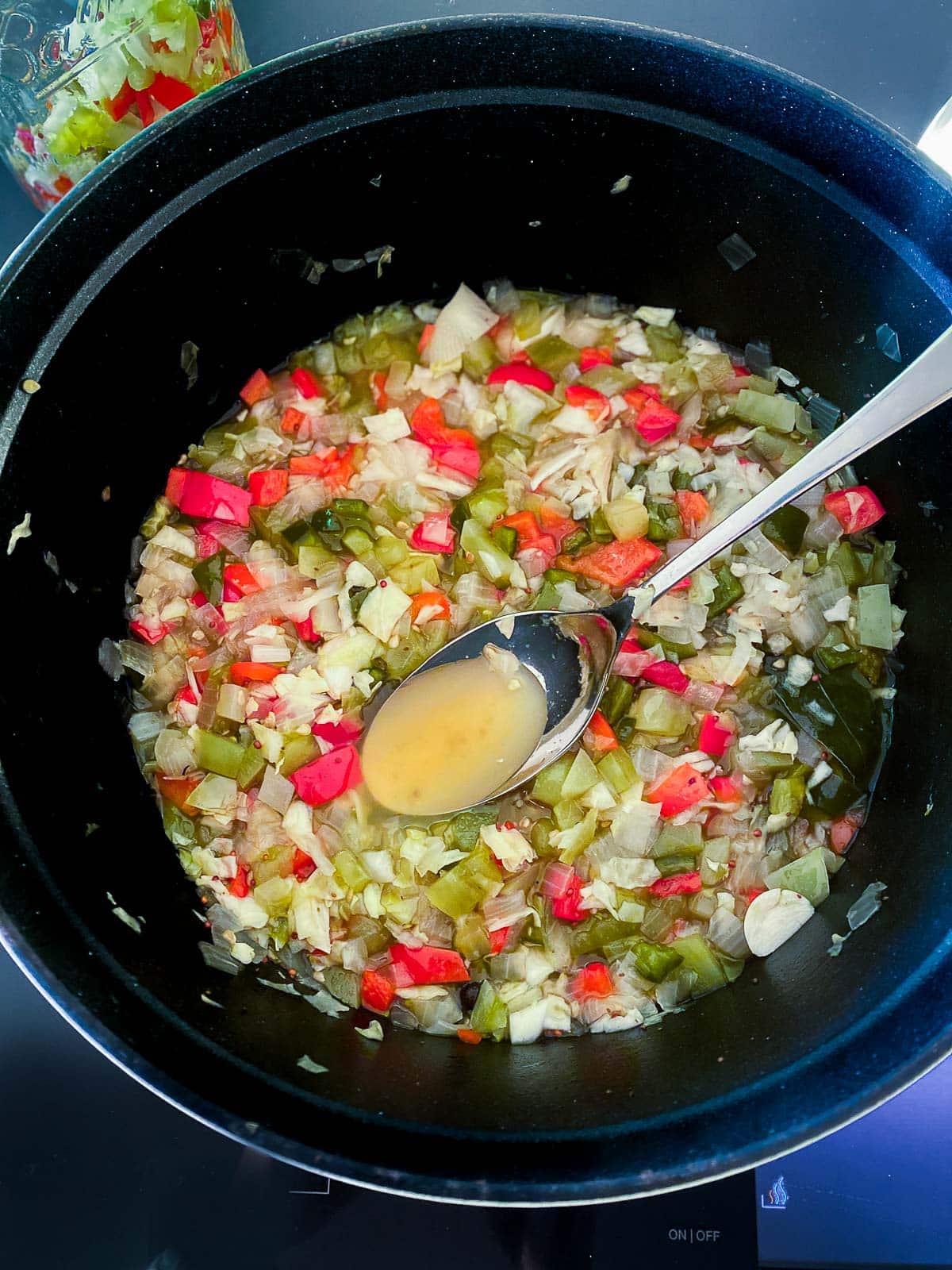 simmered veggies in pot for chow chow with spoon holding up the brine. 