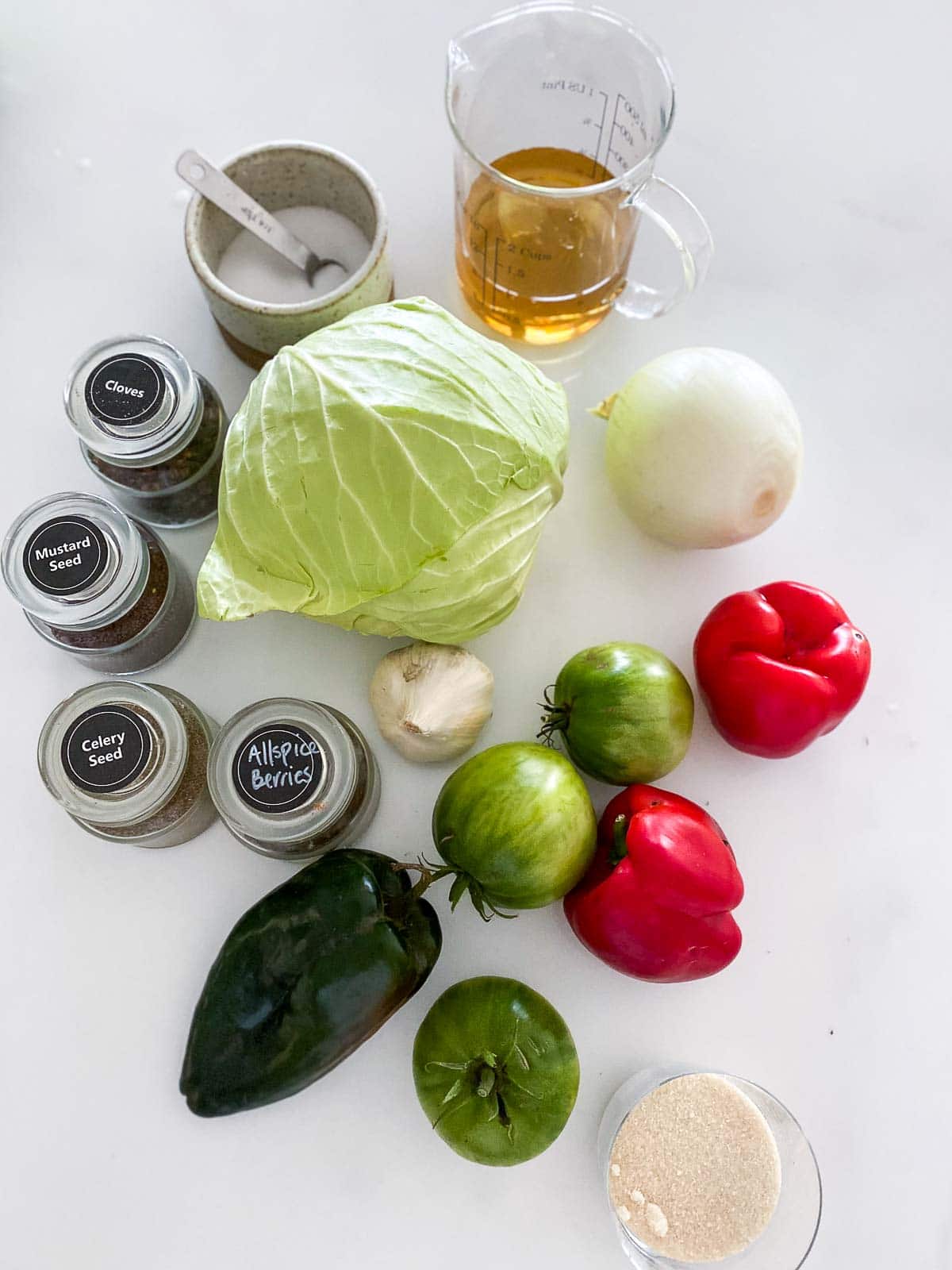 ingredients for chow chow laid out - vinegar, salt, spices, cabbage, onion, bell peppers, garlic, tomatoes, poblano, sugar. 