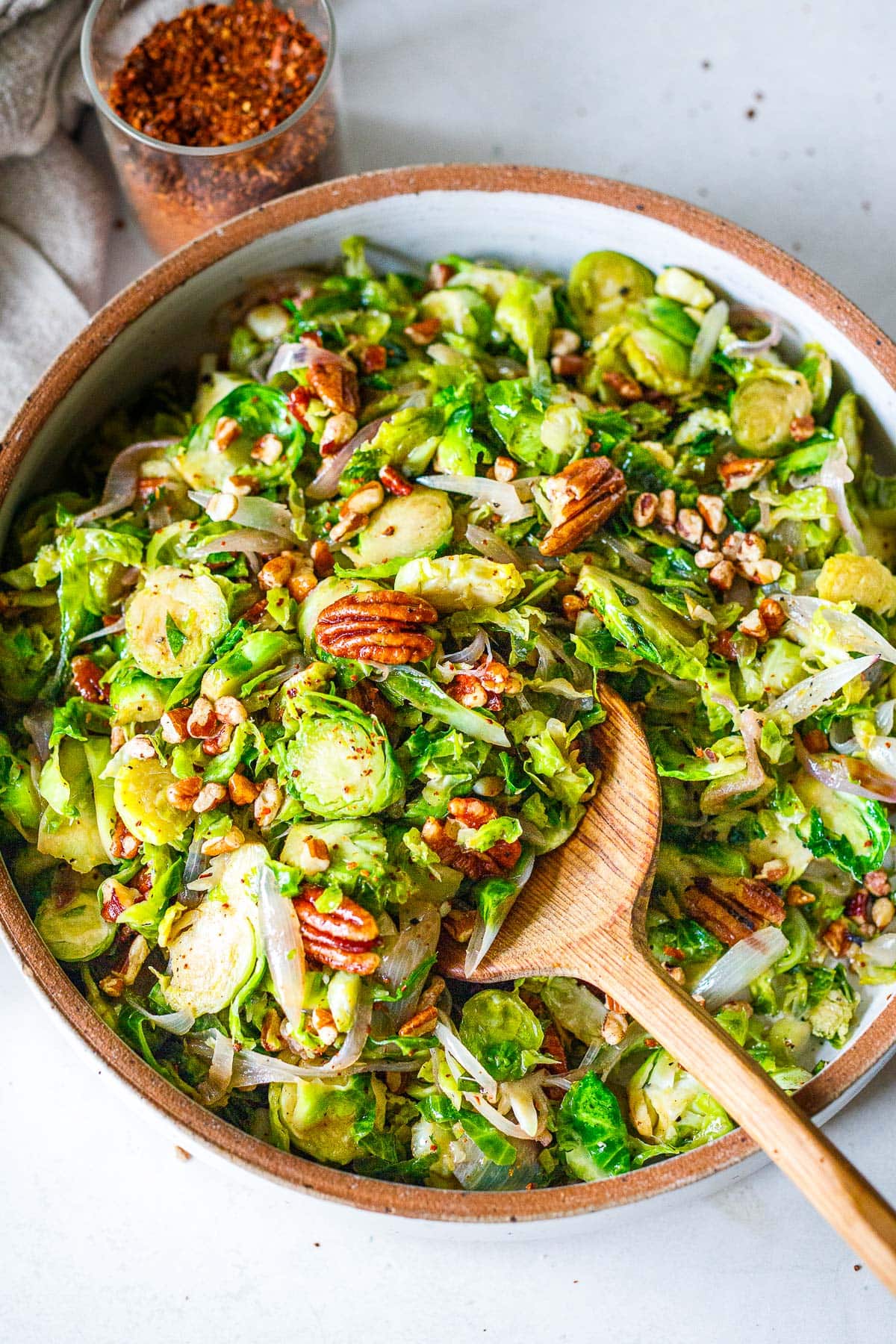 round serving dish with sauteed Brussels sprouts with shallots, pecans, and chili flakes. 