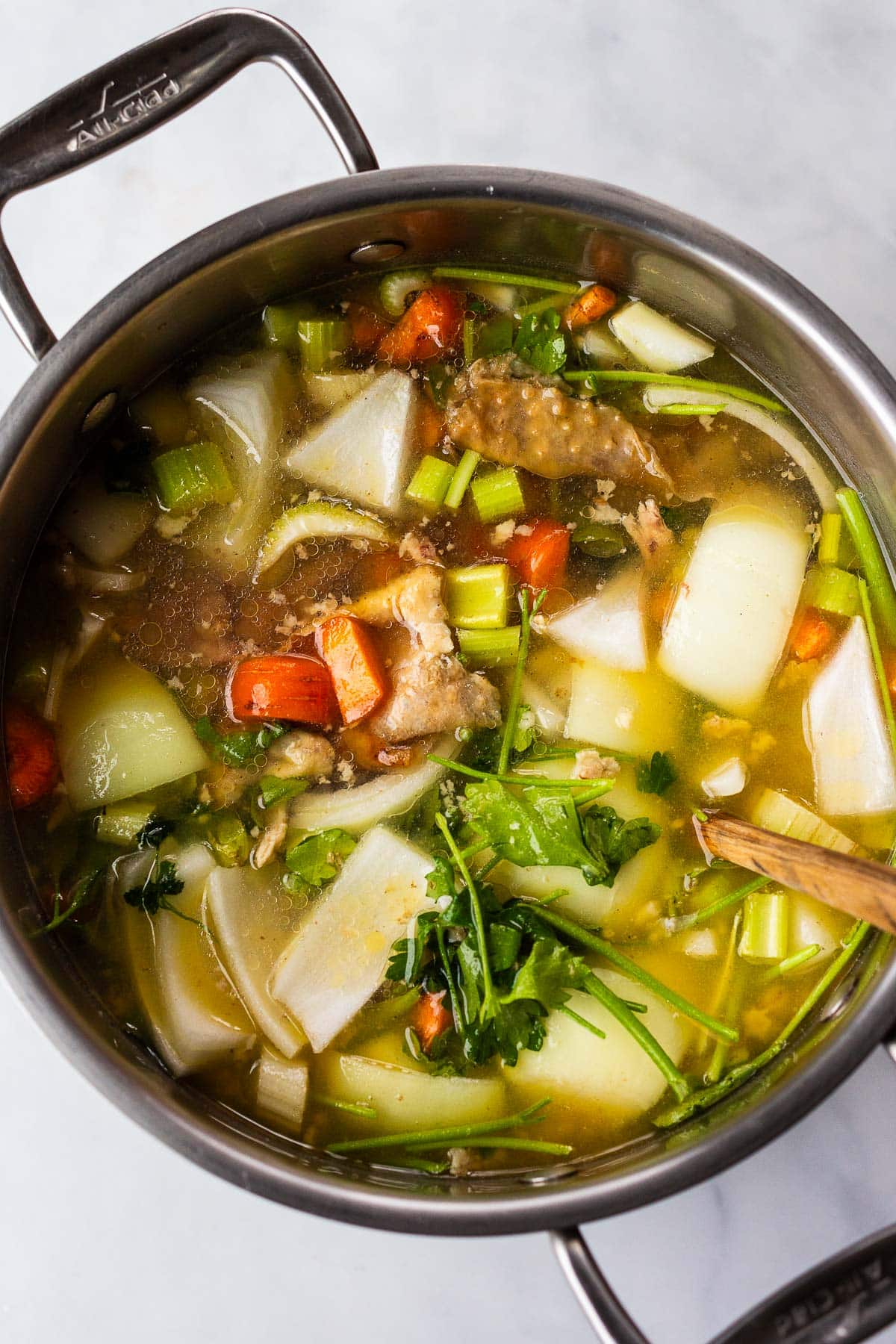 large pot with chicken stock with carcass, onions, carrots, celery, and parsley. 
