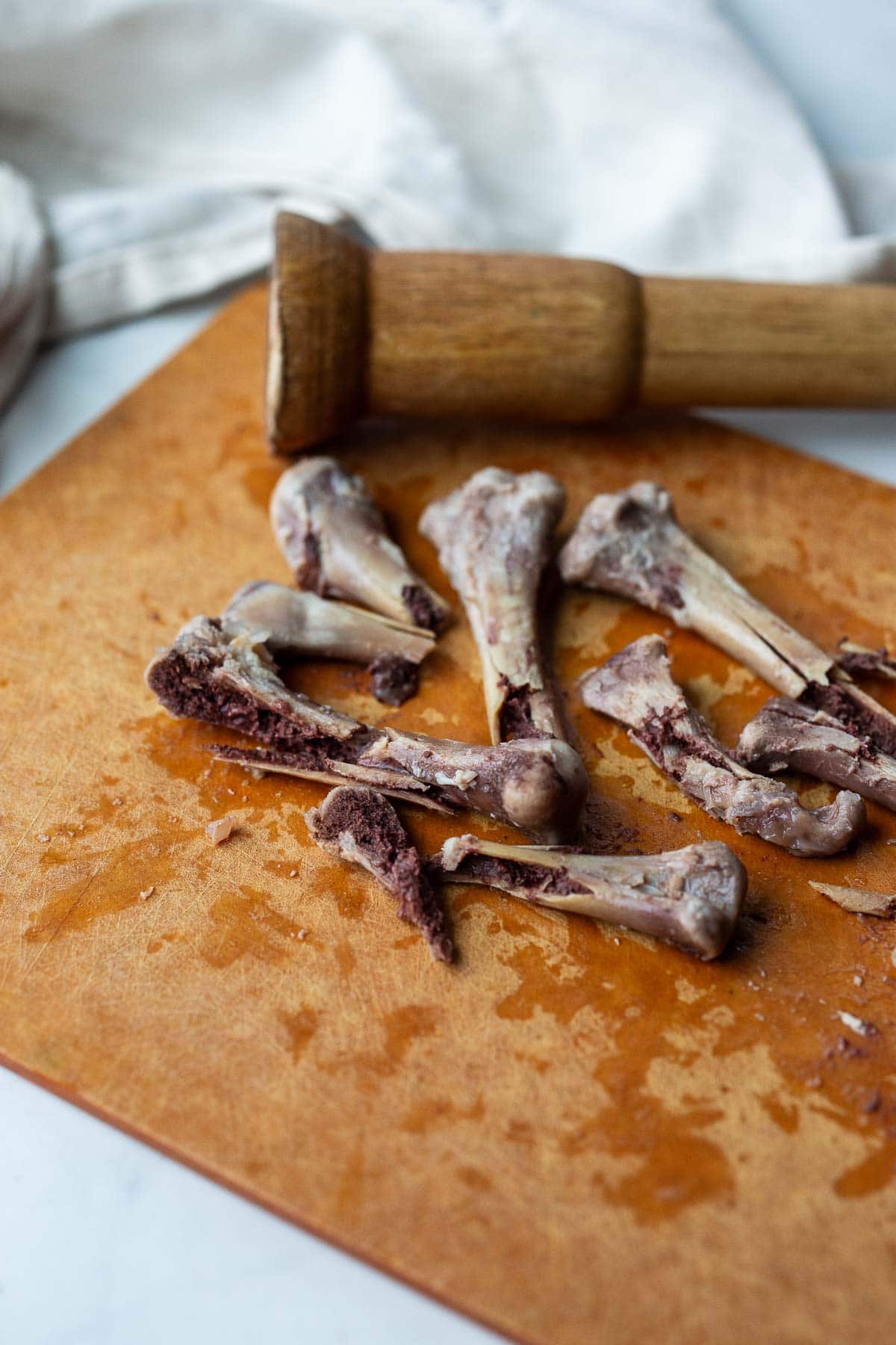 cutting board with chicken bones and mallet to smash them. 