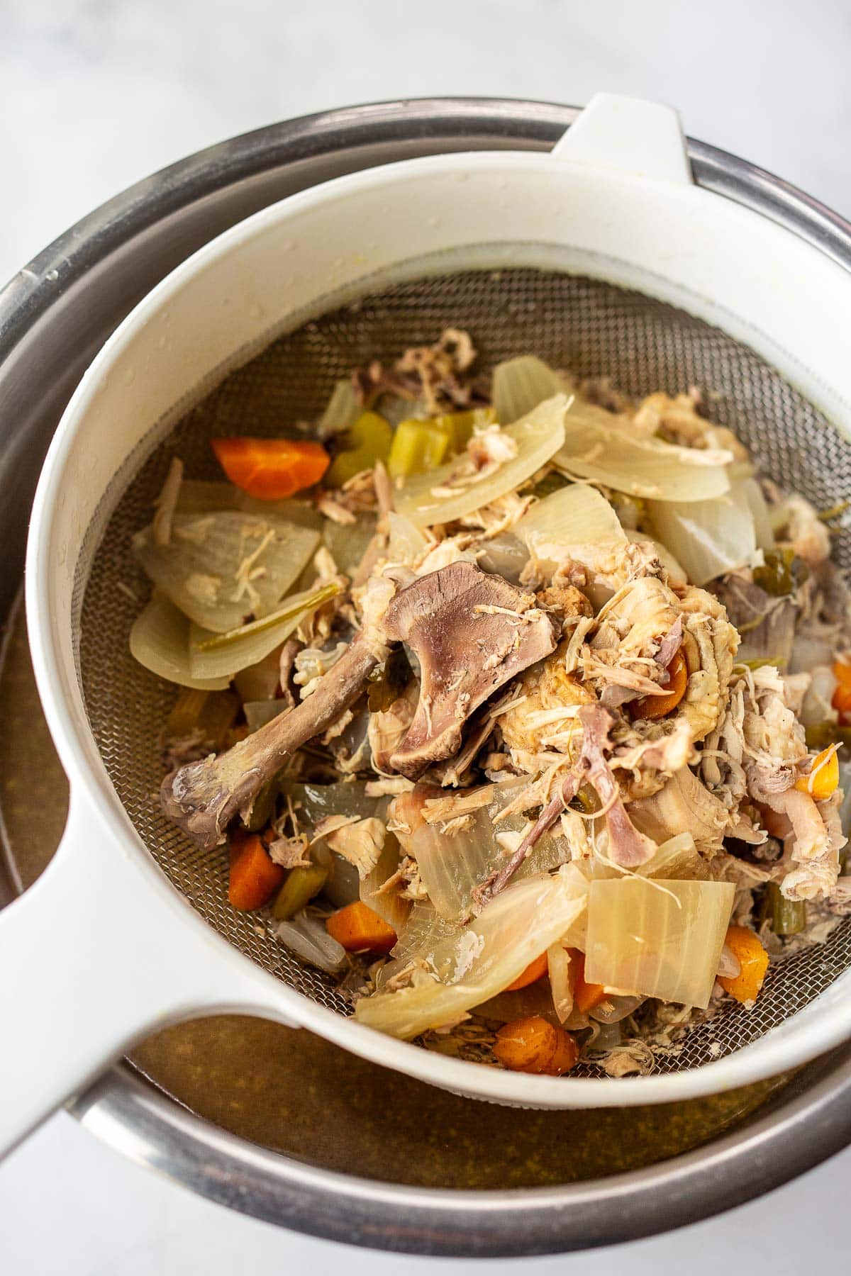 straining the chicken stock to remove carcass, bones, and large veggies. 