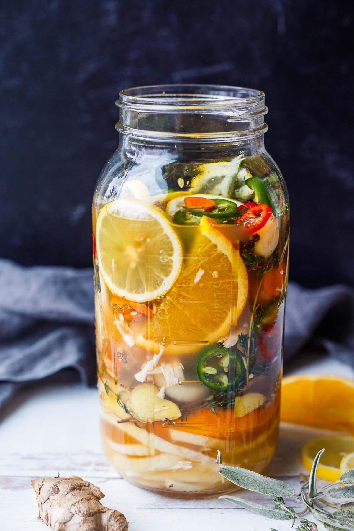mason jar with ingredients for fire cider layered with apple cider vinegar poured over top. 