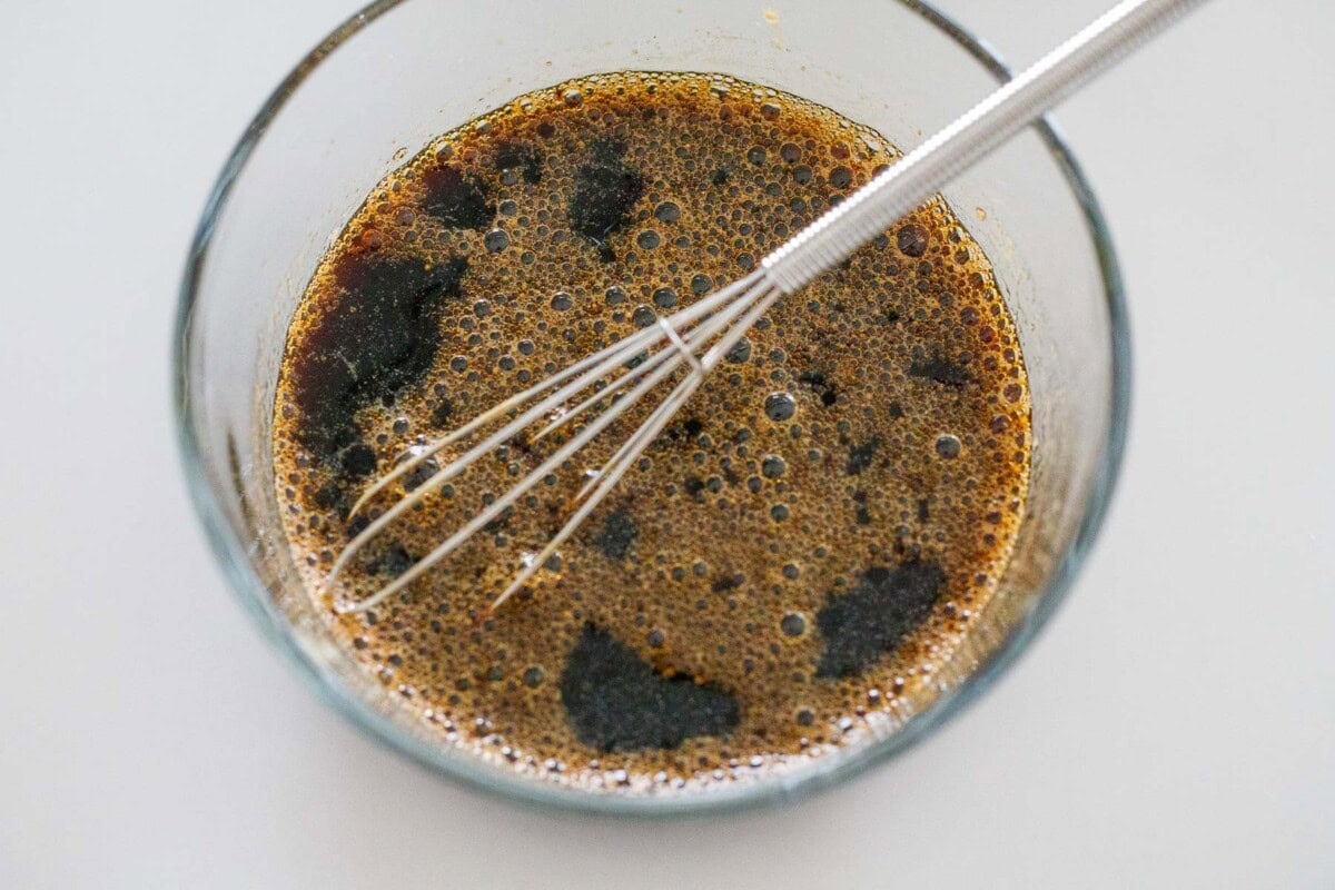 kung pao sauce in small glass bowl with whisk.