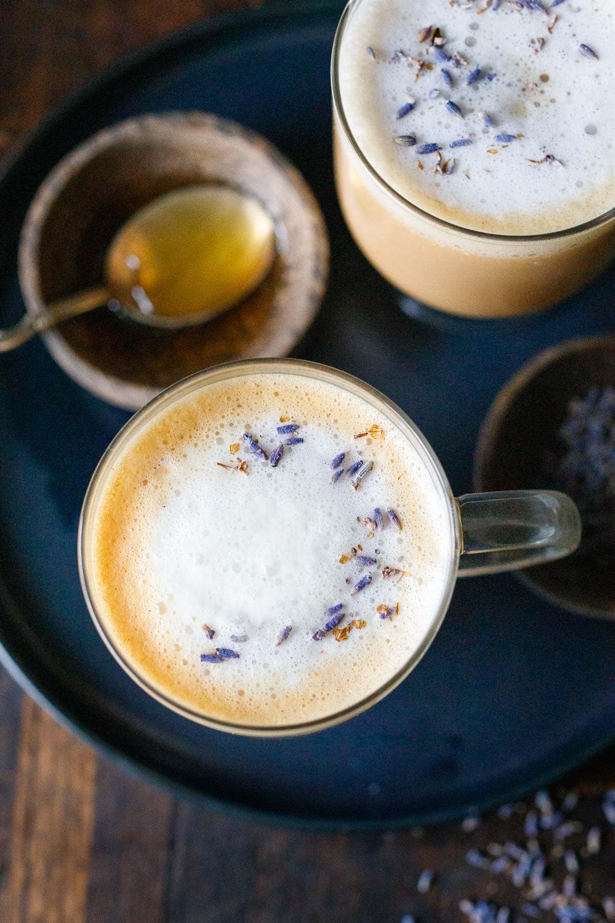top view of london fog lattes in glass mugs with frothed milk and dried lavender garnish. 