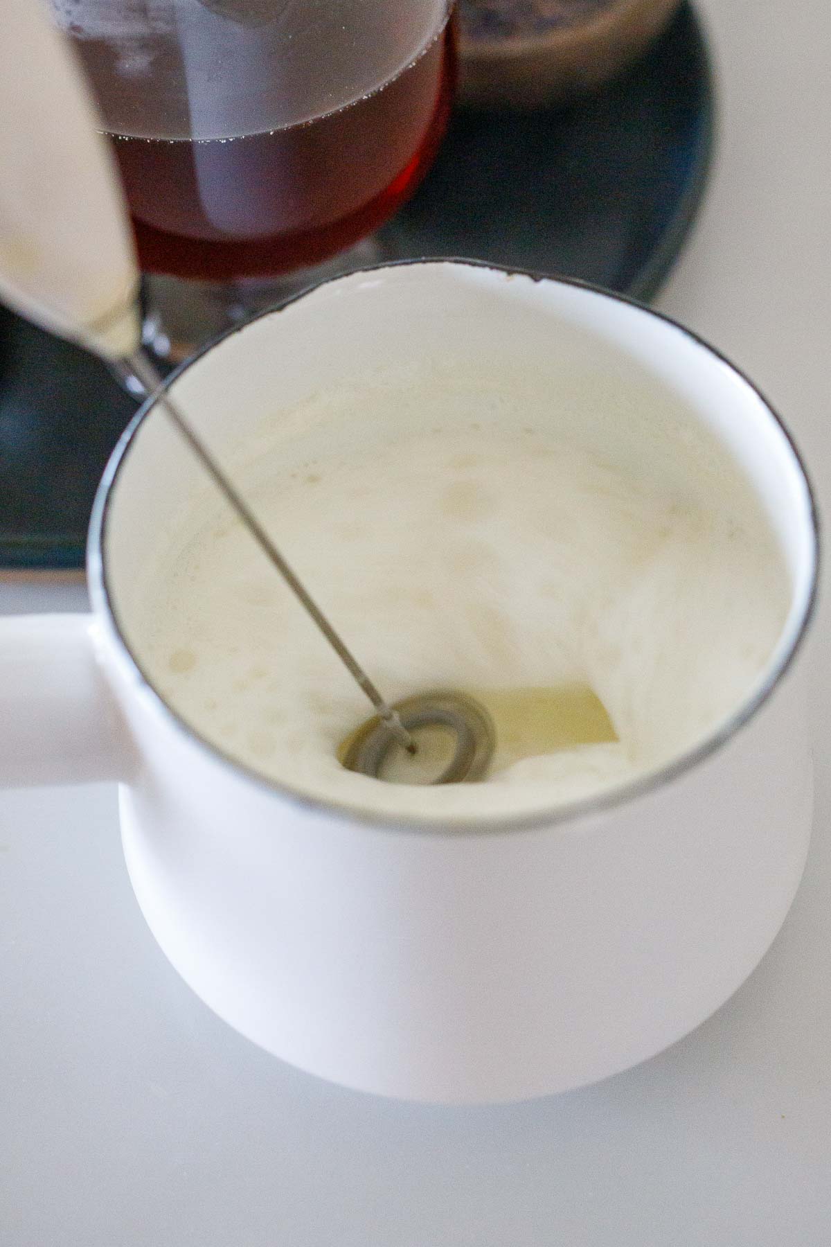 small saucepan with mini frother frothing milk. 