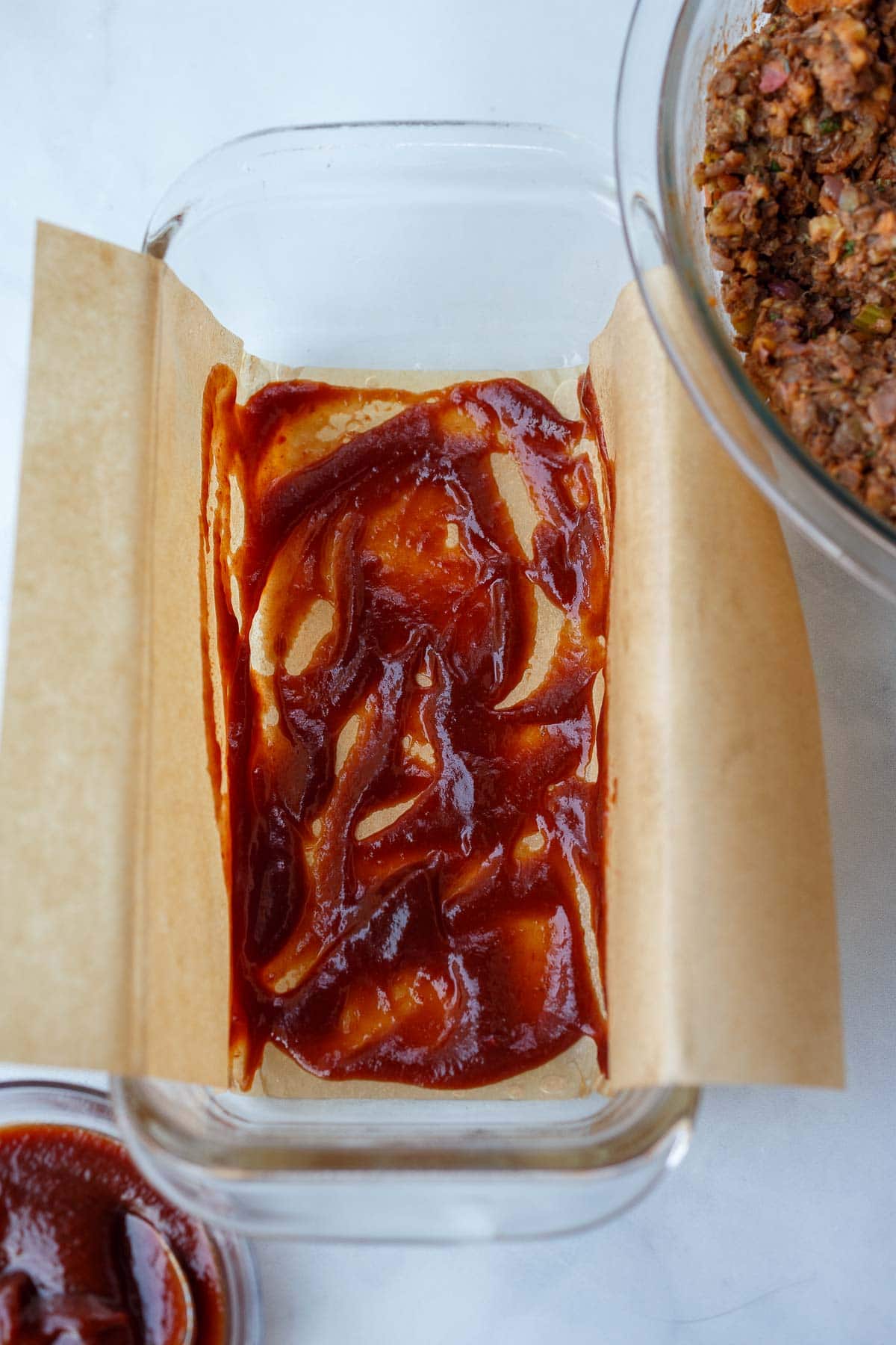 loaf pan with parchment and glaze spread over top.
