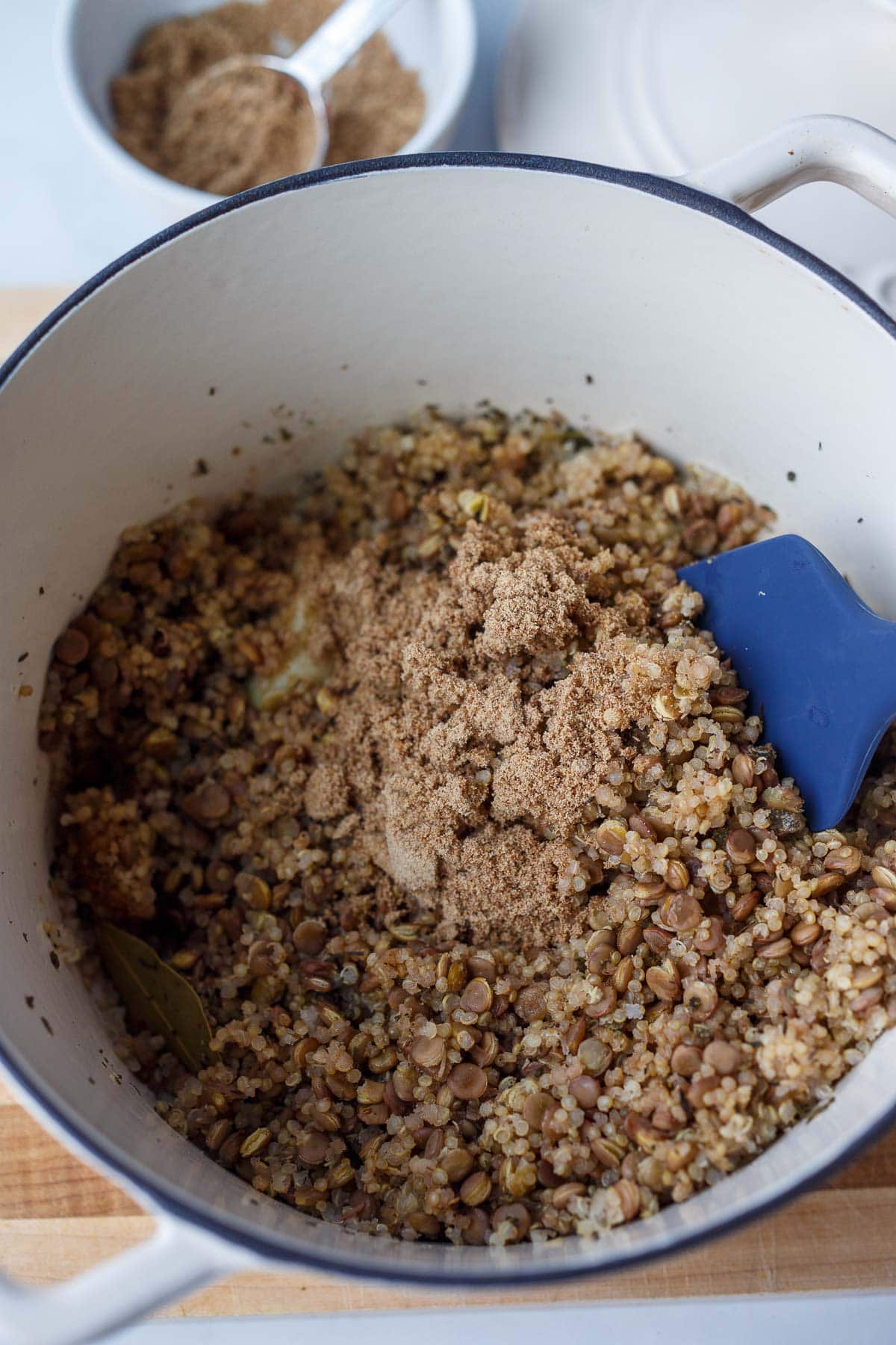 dutch oven with cooked whole grains and flaxseed sprinkled on top with spatula to stir.