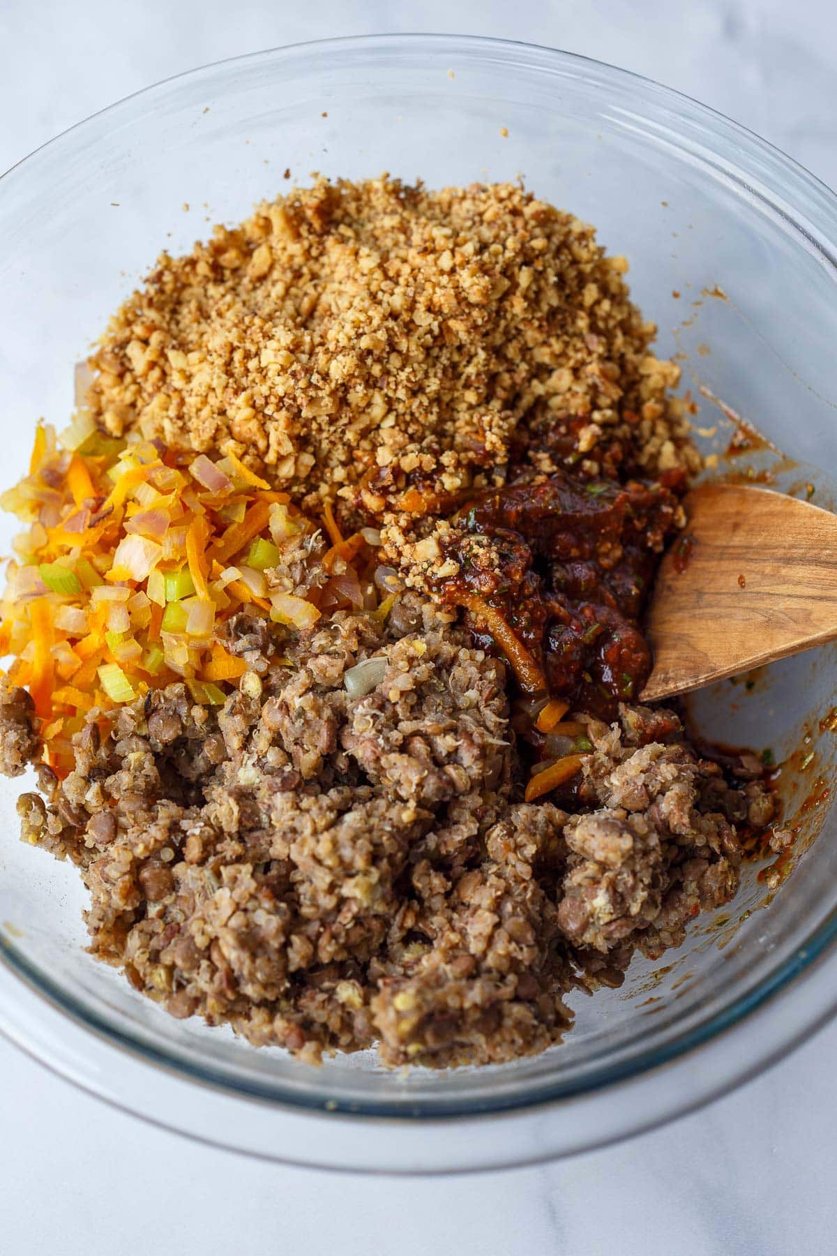 glass mixing bowl with cooked lentil mixture, pulsed walnuts, and sautéed veggies.