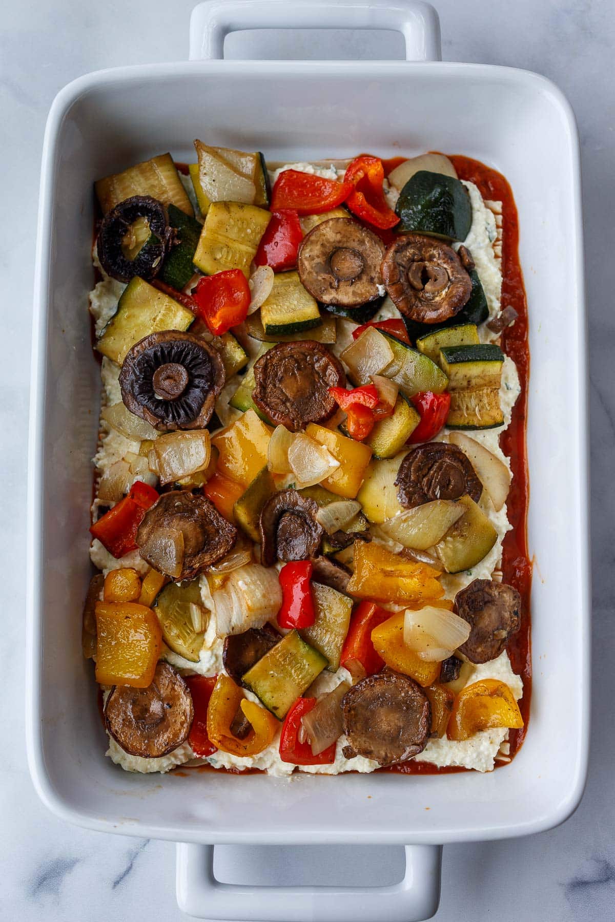 roasted veggies spread out evenly over ricotta mixture in casserole dish.