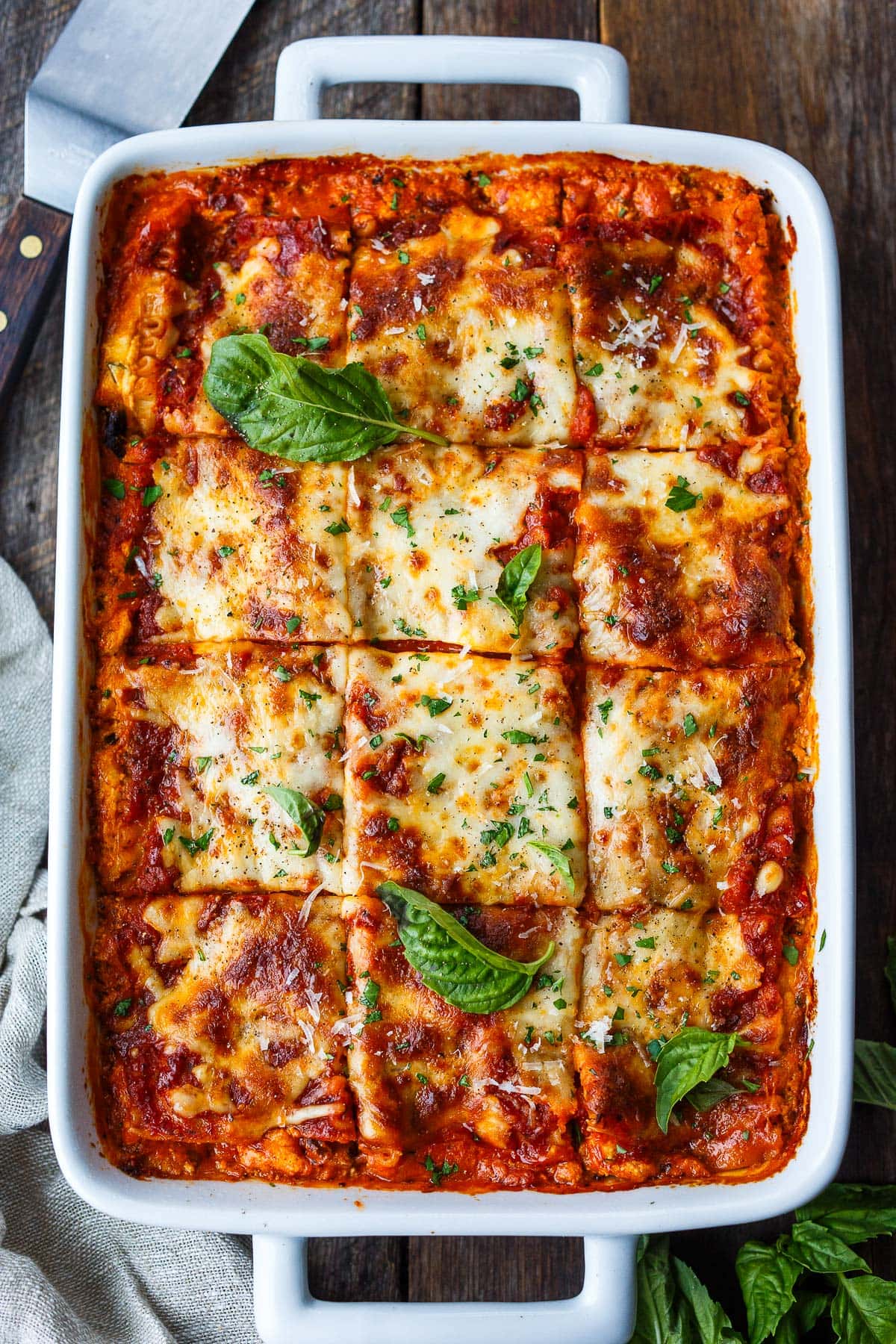 baked lasagna with fresh basil garnish and golden brown cheesy top with slice marks made.