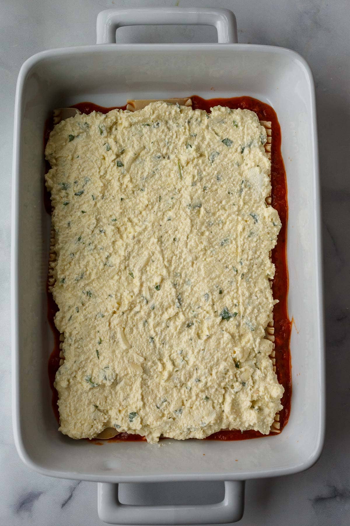 ricotta mixture spread over top of the lasagna noodles in casserole dish.