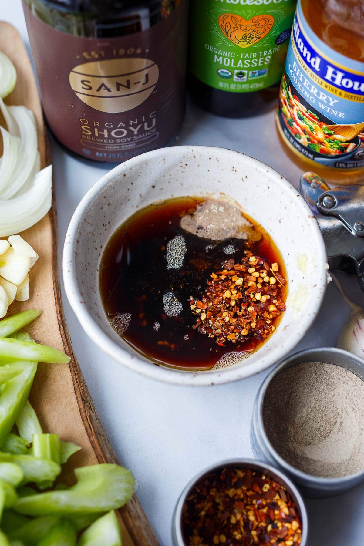 small bowl with ingredients for stir-fry sauce added to it, surrounded by individual ingredients. 
