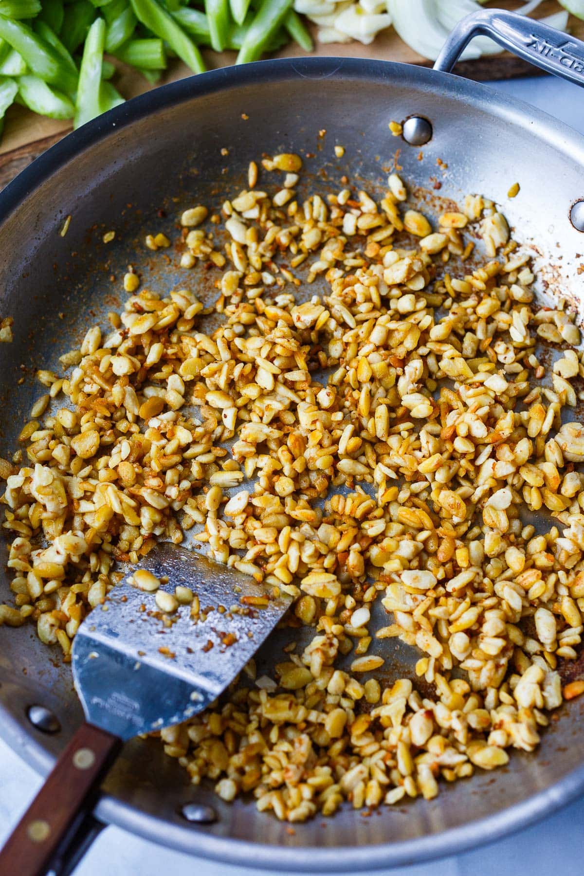 skillet with crumbled tempeh beginning to brown with spatula to stir.