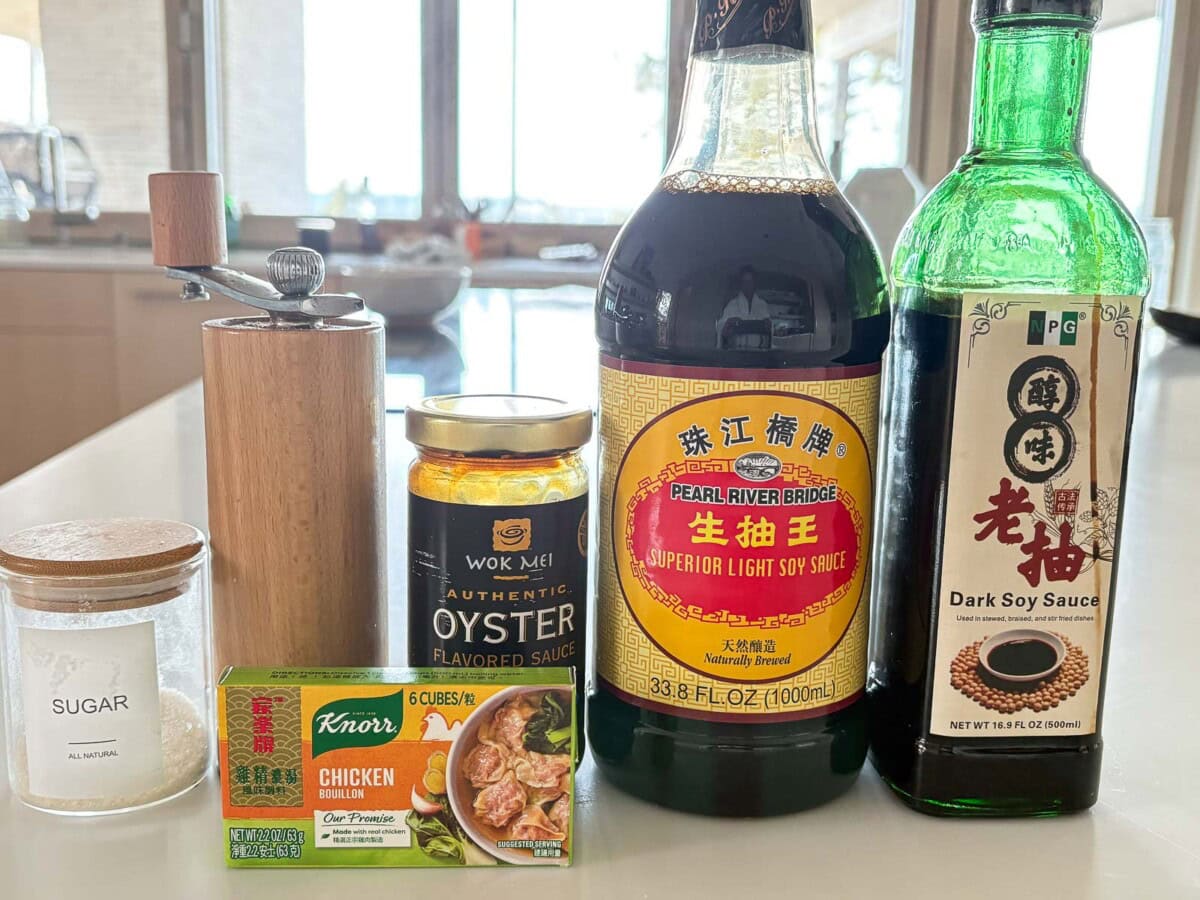 some of the ingredients to make char kway teow arranged on a table - sugar, pepper, chicken bouillon, oyster sauce, light soy sauce, dark soy sauce.