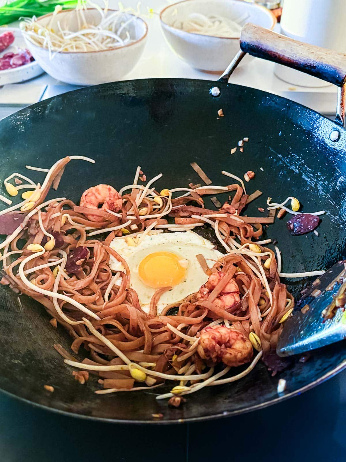 well made in center of char kway teow in wok for a cracked egg to cook.