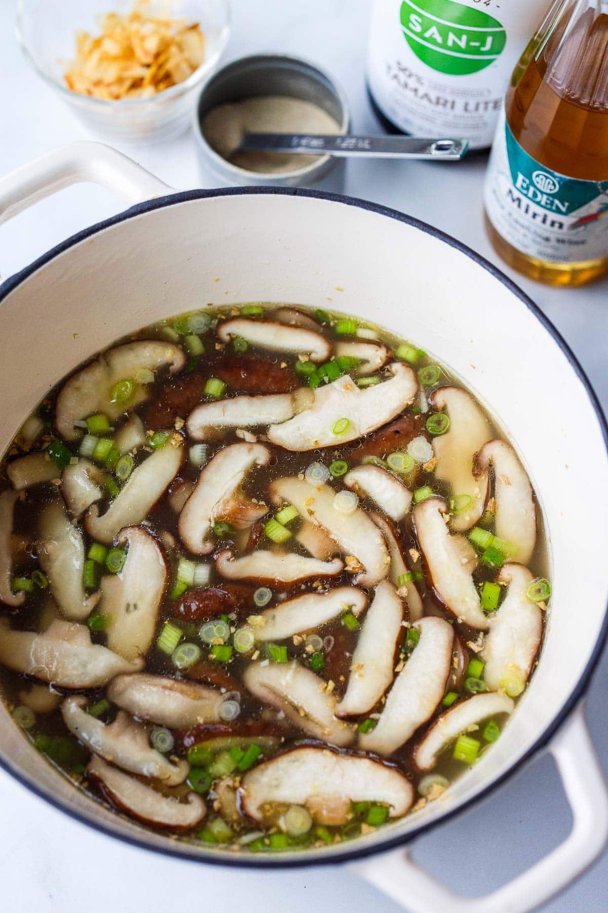 simmering ramen broth with shiitake mushrooms and green onions.