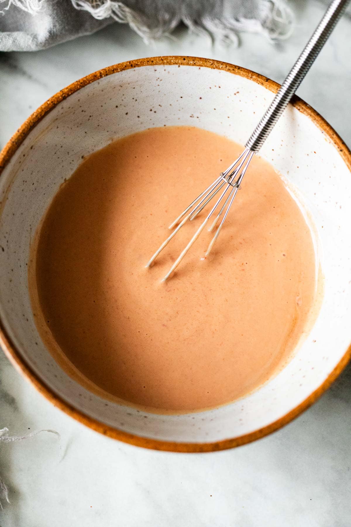 ceramic bowl with yum yum sauce and whisk. 