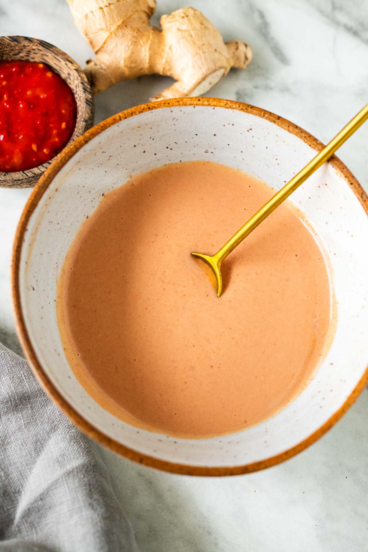yum yum sauce in ceramic bowl with gold spoon.