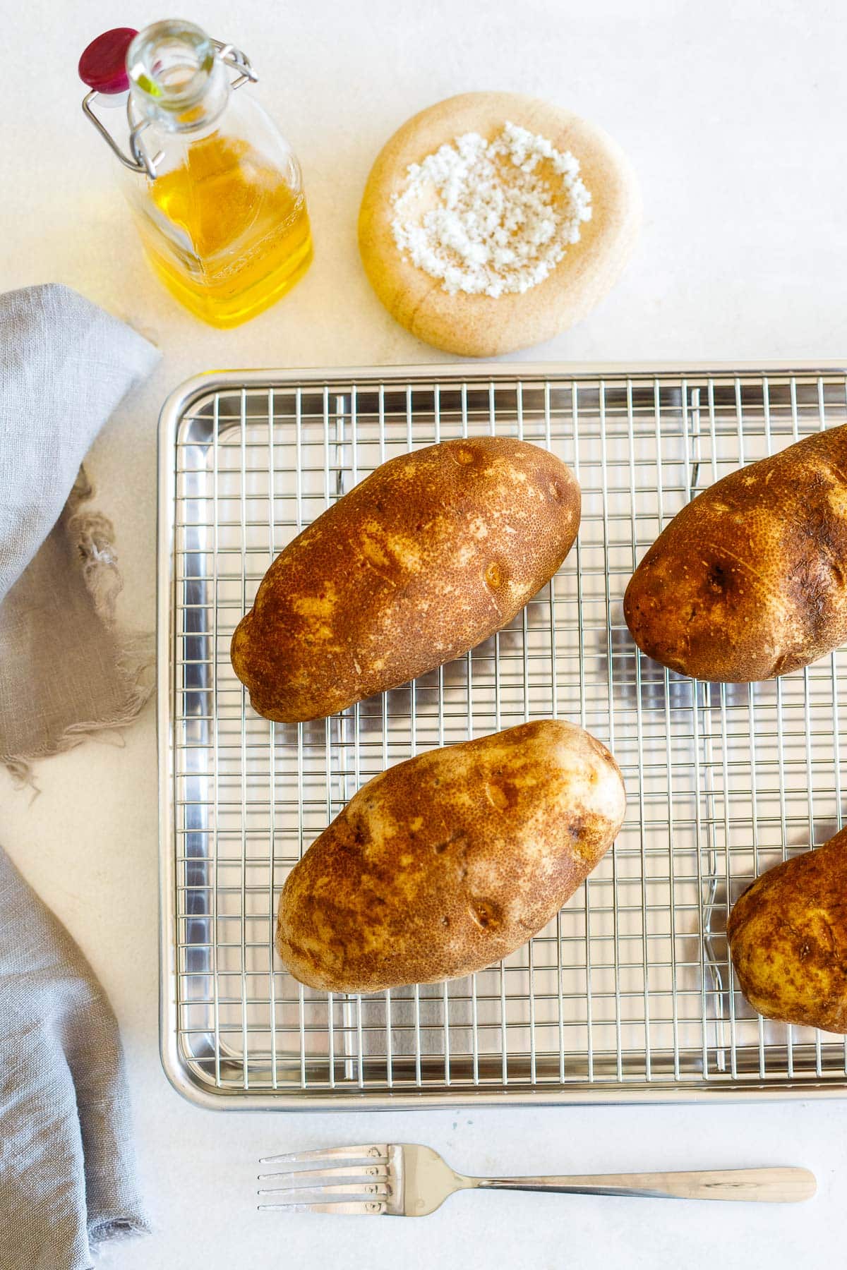scrubbed russet potatoes on a wire rack on a baking sheet.