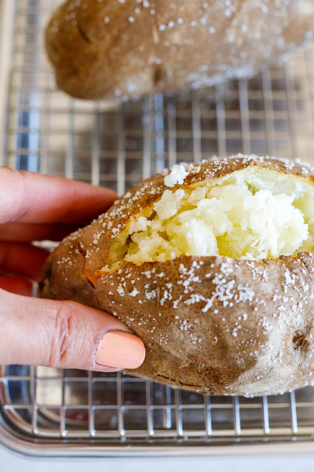 fingers pushing open a baked potato. 