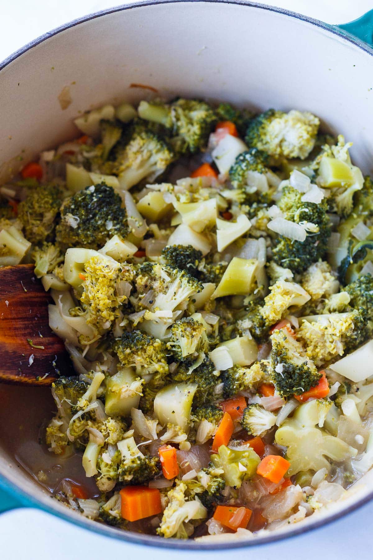 soup pot with cooked broccoli, carrots, and onion in broth.