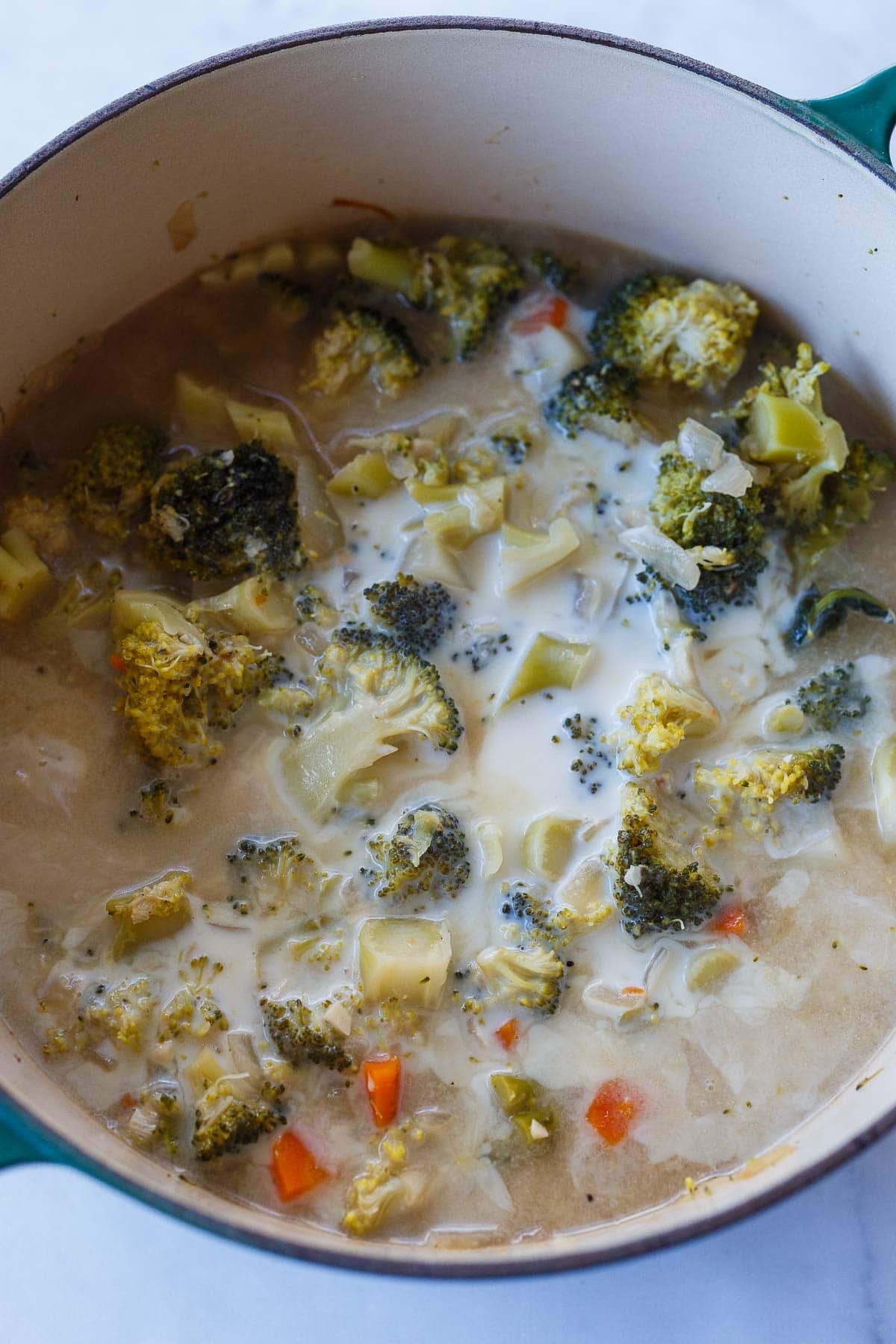 soup pot with broccoli cheddar soup before blending with cooked broccoli and milk added.