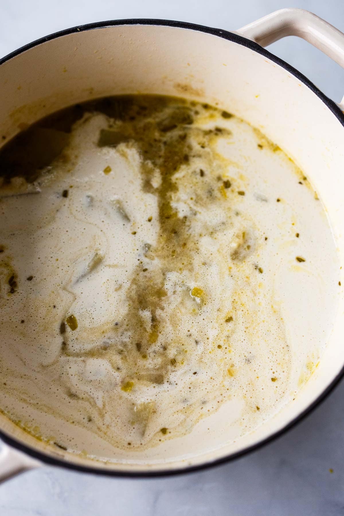 dutch oven with simmering potato soup with leek broth and milk. 