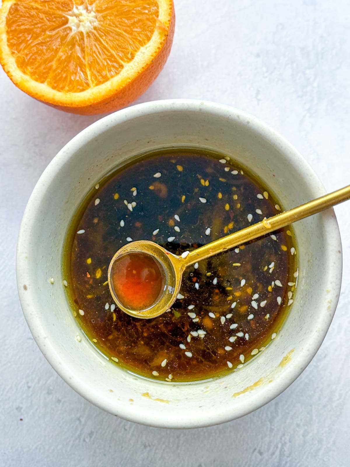 gold spoon in small bowl of chinese chicken salad dressing.