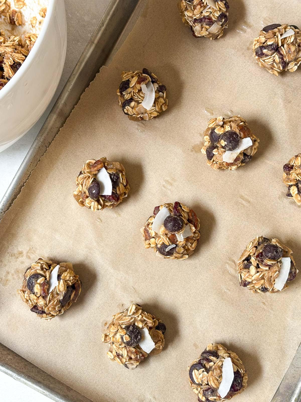 parchment lined baking sheet with cowgirl cookie batter rolled into balls and arranged neatly on the pan ready to bake.