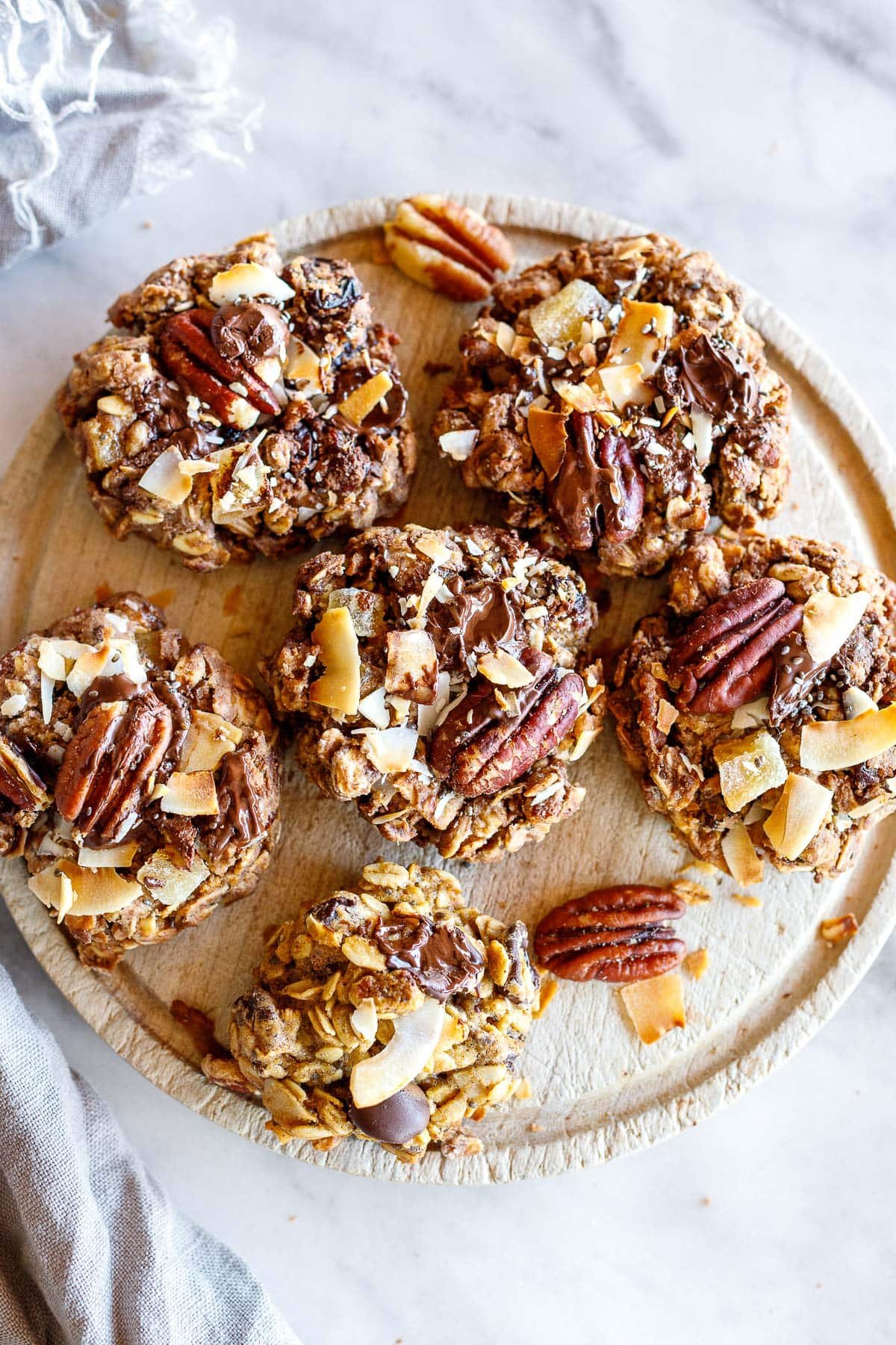 wood circle serving board with cowgirl cookies topped with toasted coconut and pecans.