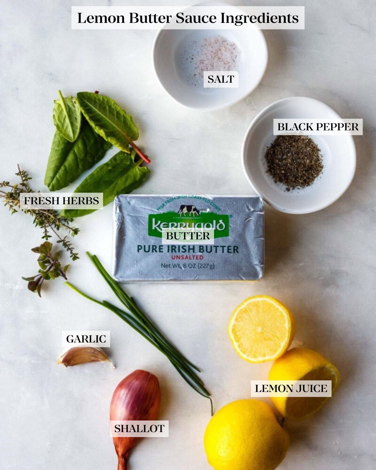 ingredients for lemon butter sauce- small dishes with salt and pepper, fresh herbs, block of unsalted Kerrygold Pure Irish Butter, halved lemons, shallot, and garlic clove.