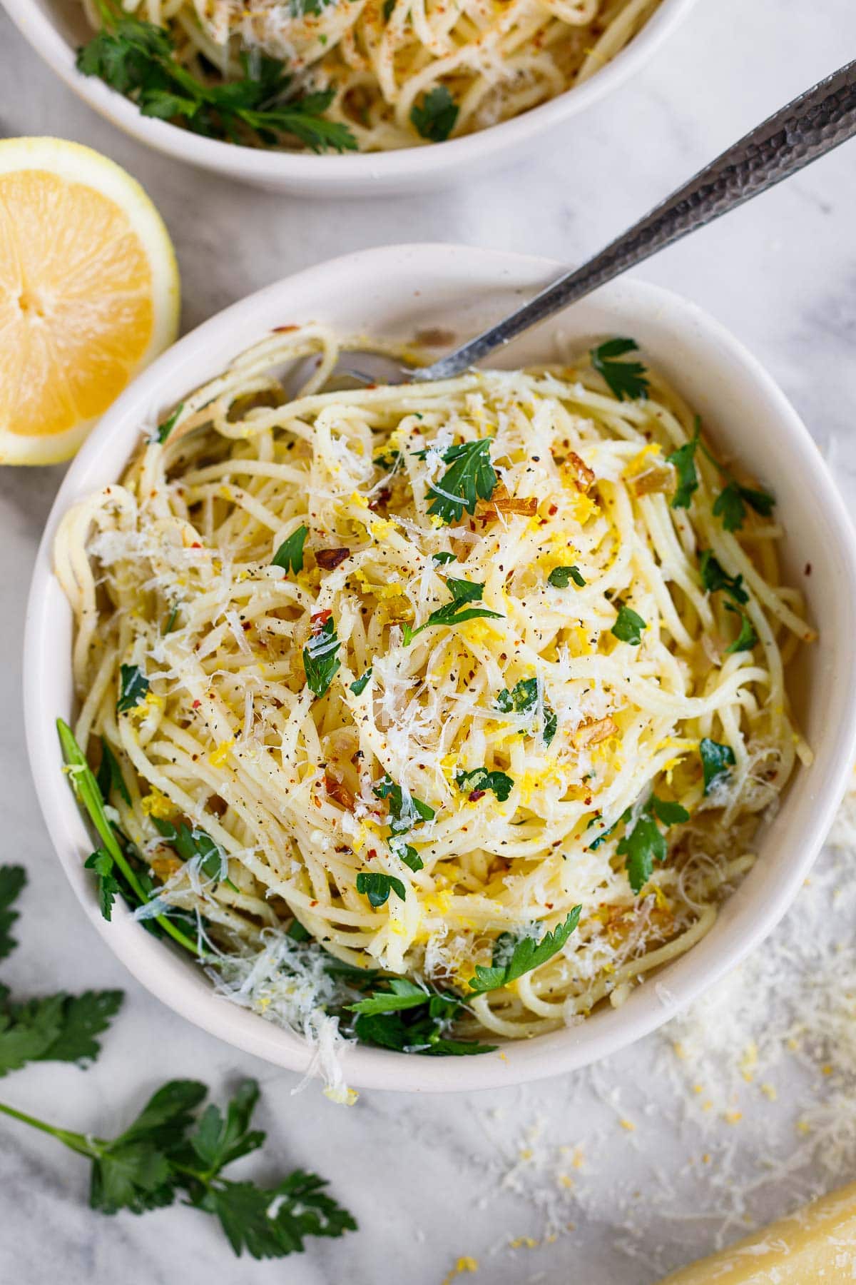 bowl of lemon pasta garnished with lemon zest, parsley, and pecorino.
