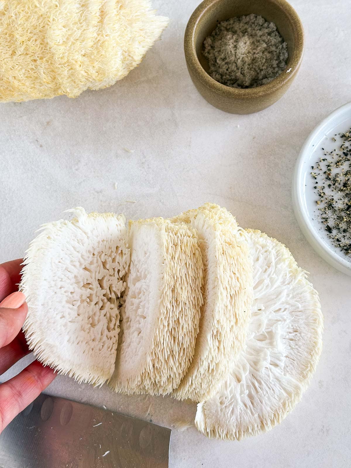 hand showing sliced lion's mane mushroom.