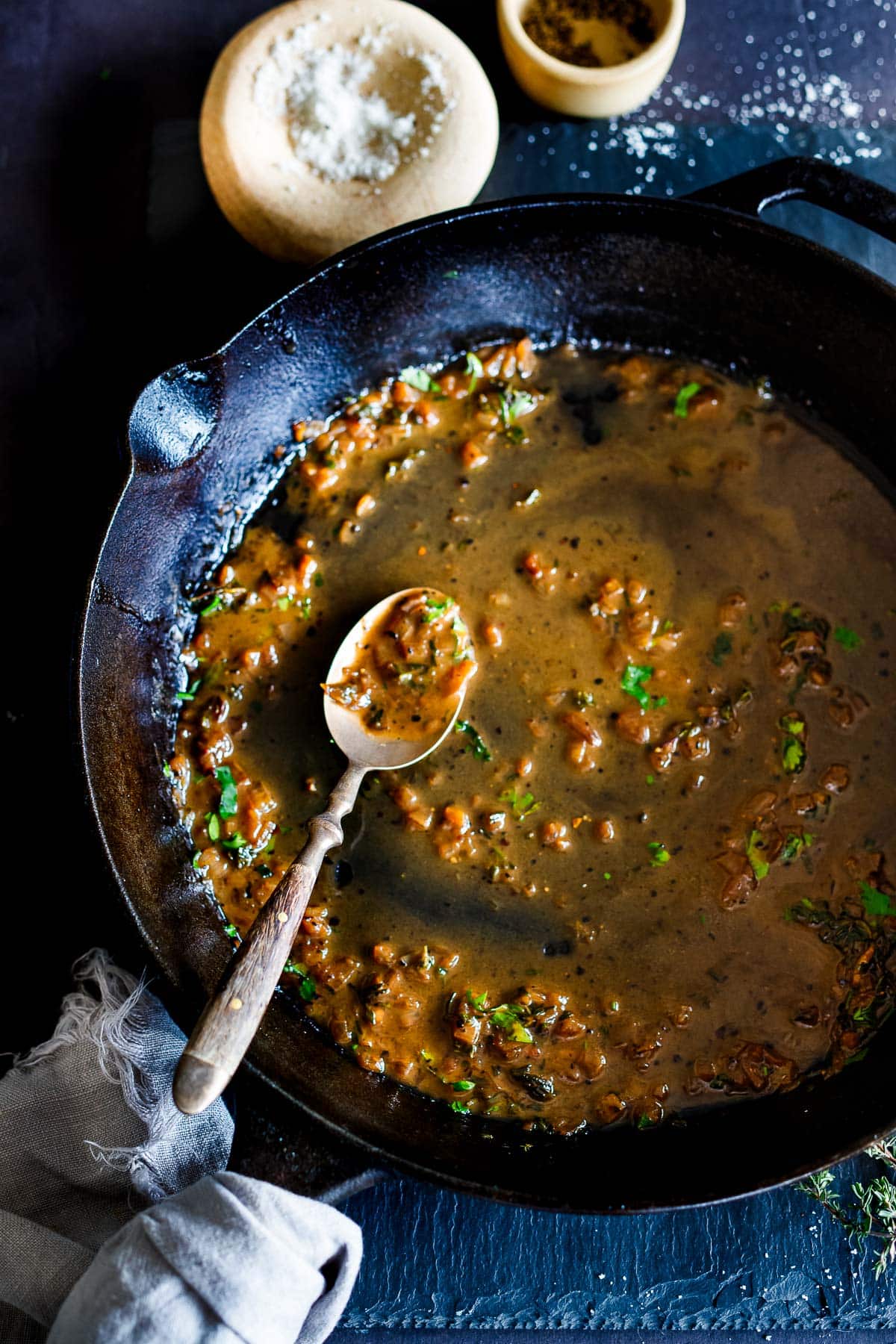 pan sauce in cast iron skillet topped with fresh herbs with a spoon in the pan. 