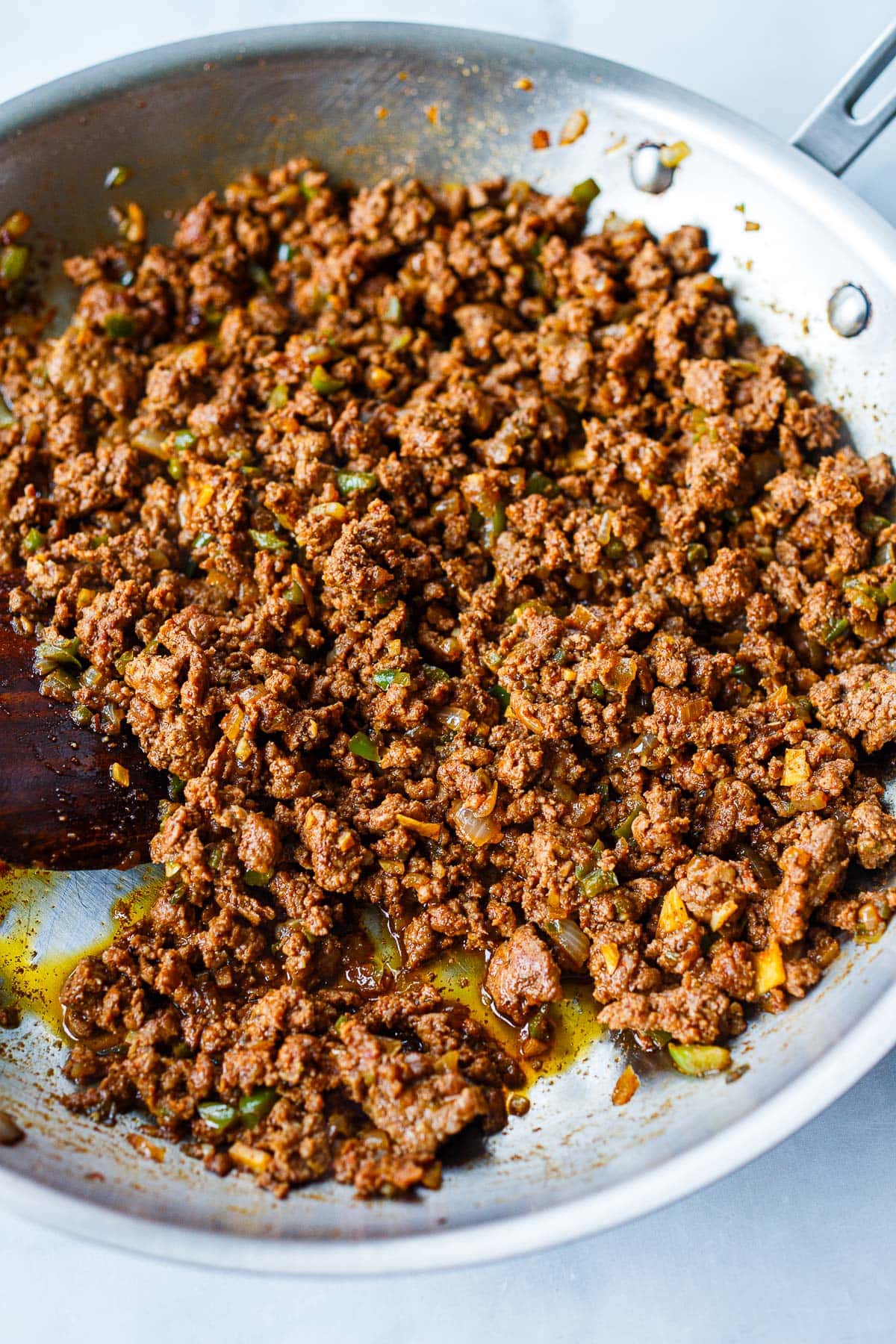 ground beef cooking in skillet with spices and minced veggies. 